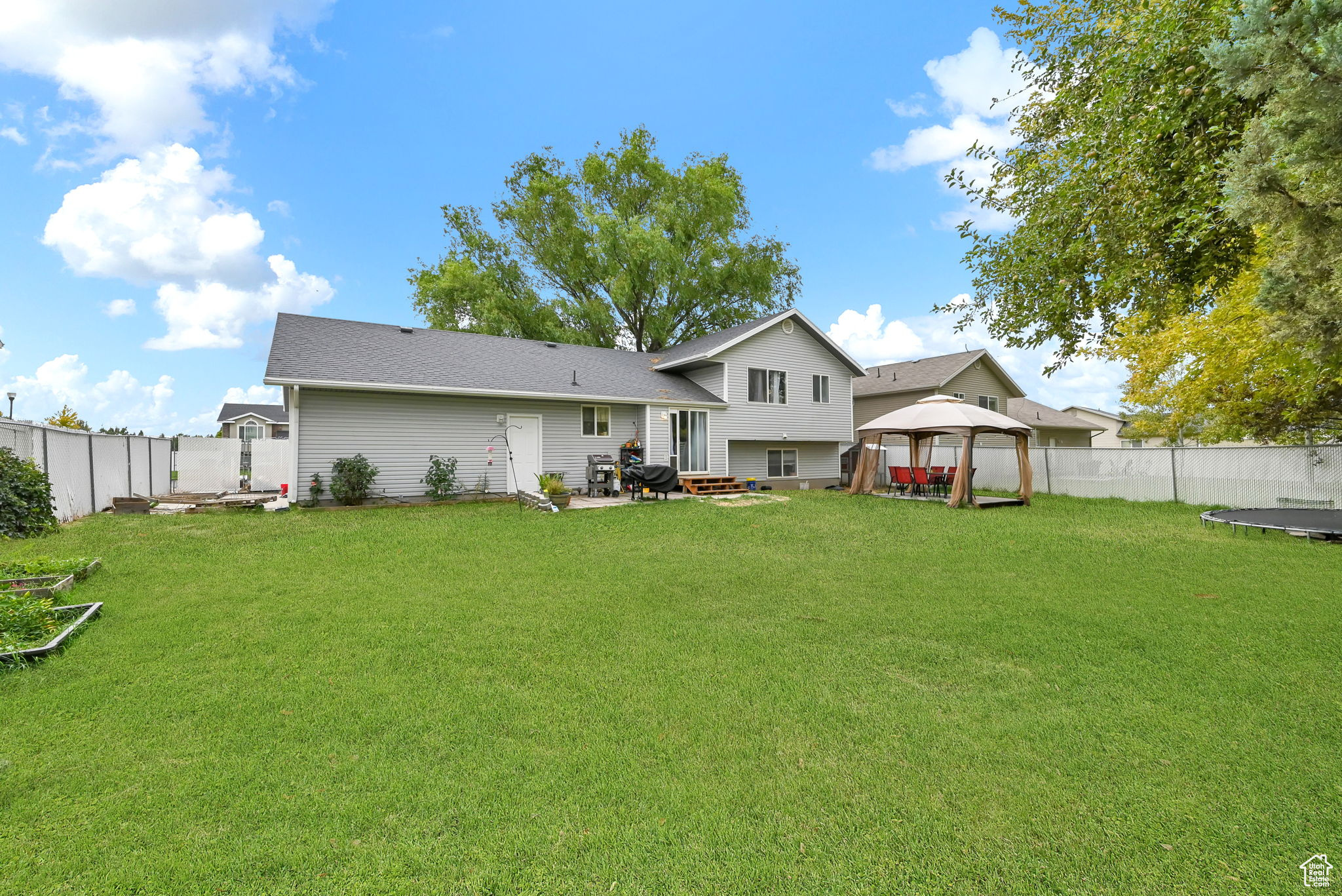 Rear view of property featuring a gazebo, a trampoline, and a yard