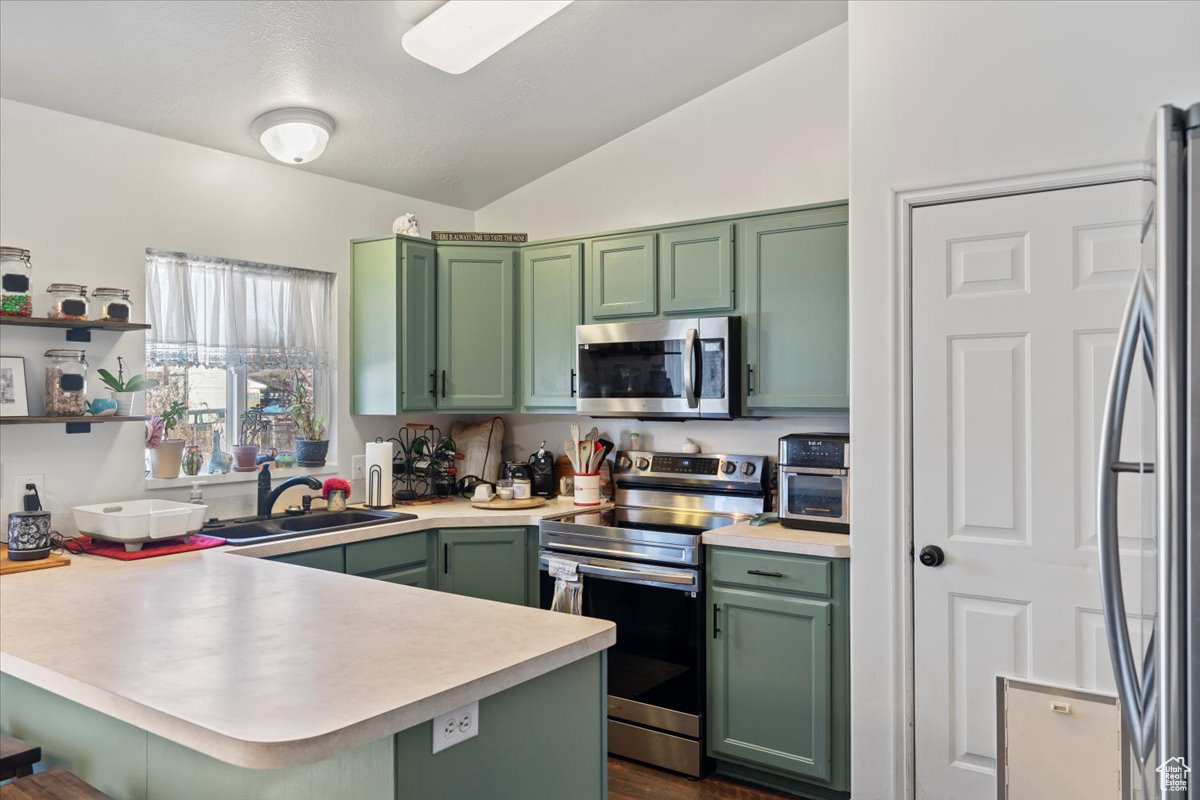 Kitchen featuring sink, appliances with stainless steel finishes, kitchen peninsula, and green cabinetry