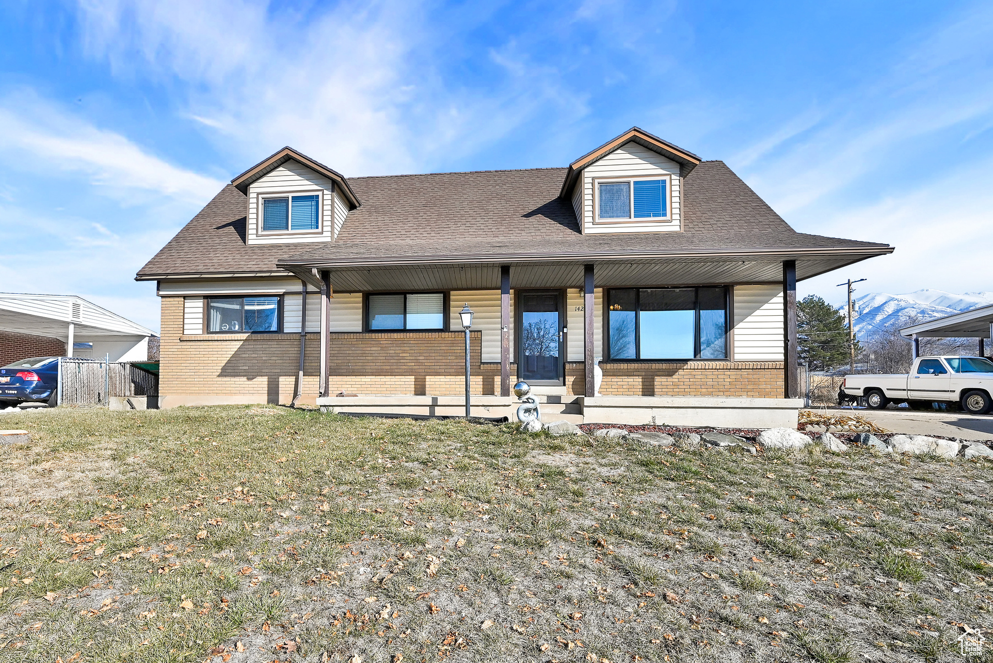 View of front of home featuring covered porch, a front lawn, and a mountain view