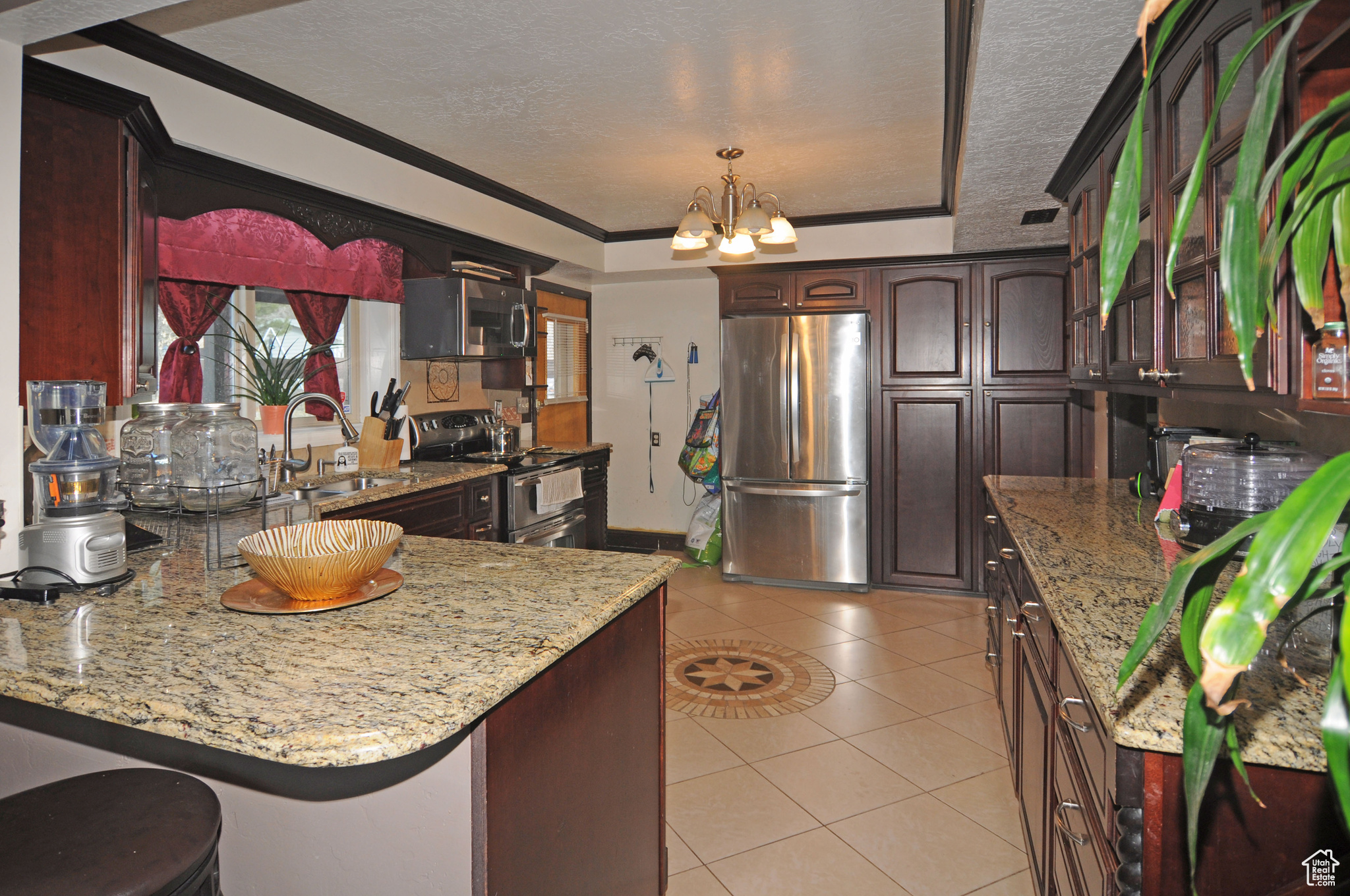 Kitchen featuring sink, decorative light fixtures, light stone countertops, and appliances with stainless steel finishes