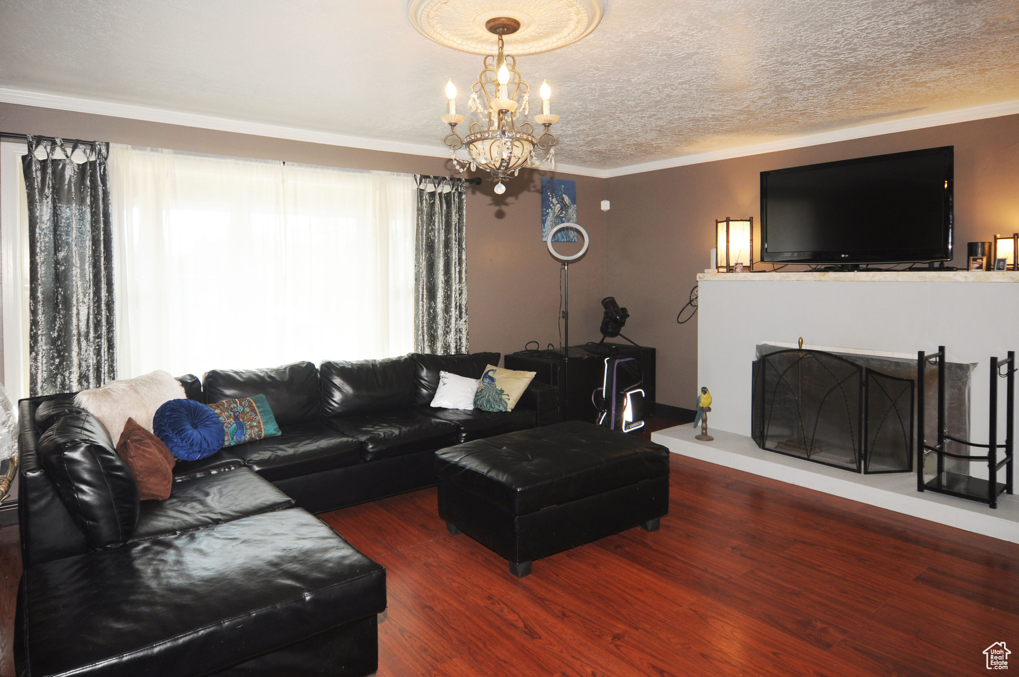 Living room with hardwood / wood-style floors, crown molding, a notable chandelier, and a textured ceiling