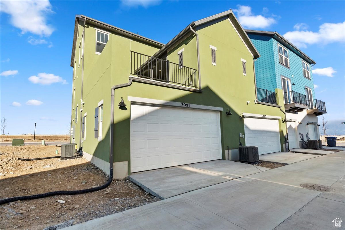 View of home's exterior with a balcony, central AC, and a garage