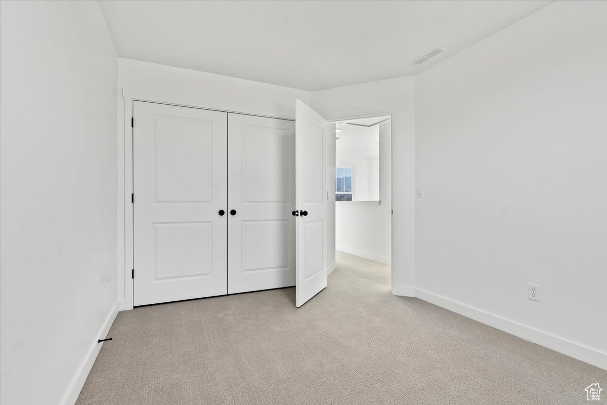 Unfurnished bedroom with light colored carpet and a closet