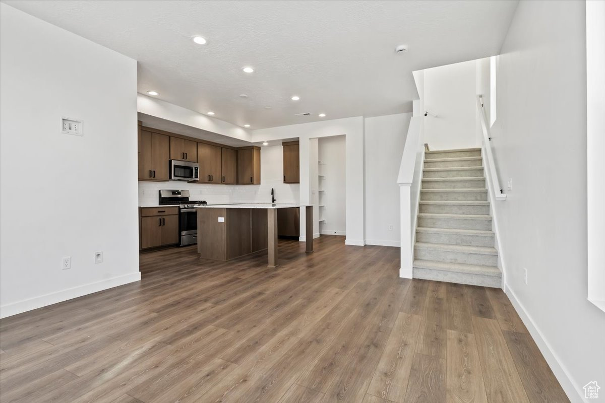 Kitchen with a kitchen breakfast bar, appliances with stainless steel finishes, light hardwood / wood-style flooring, and a kitchen island