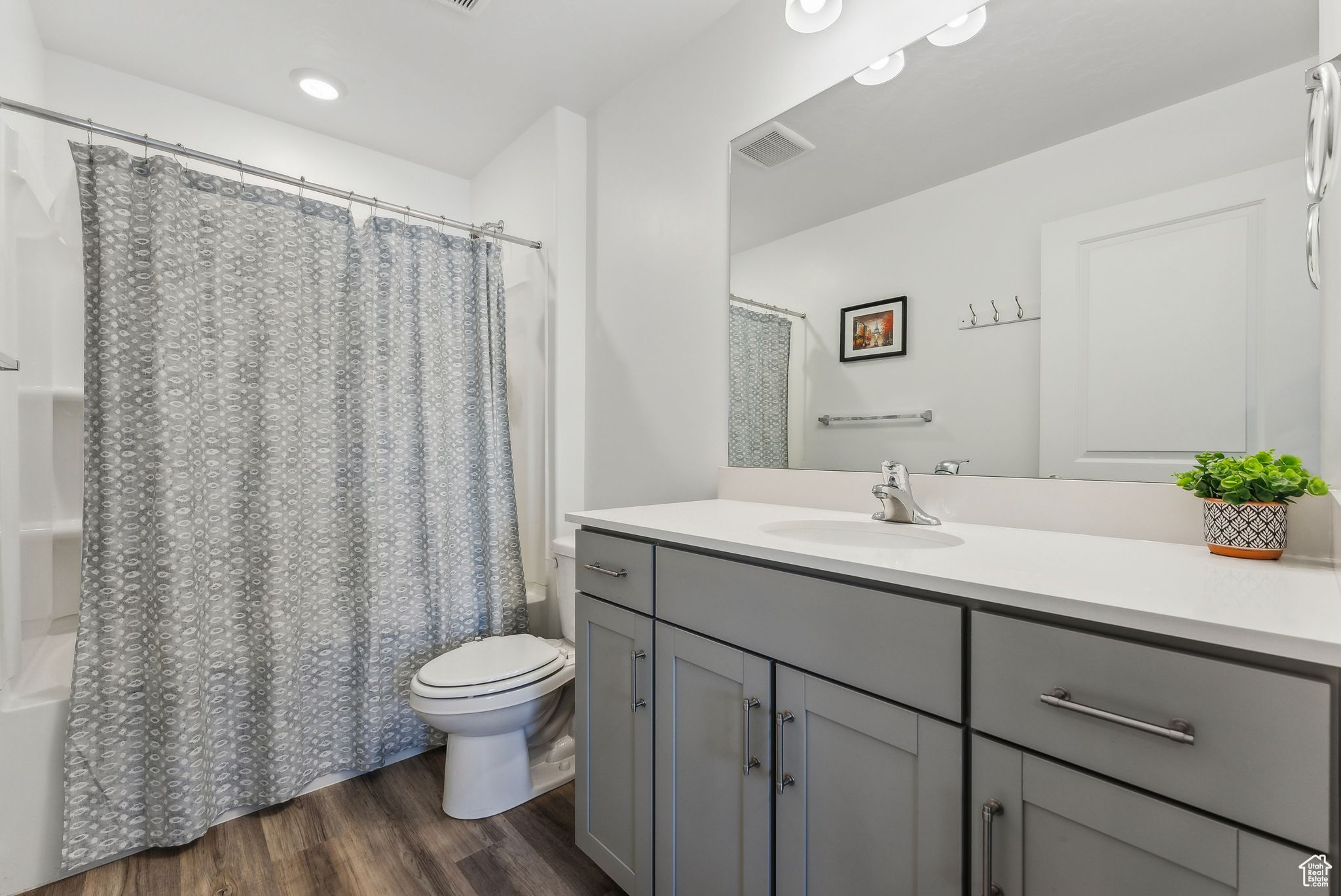 Full bathroom with wood-type flooring, toilet, shower / tub combo, and vanity