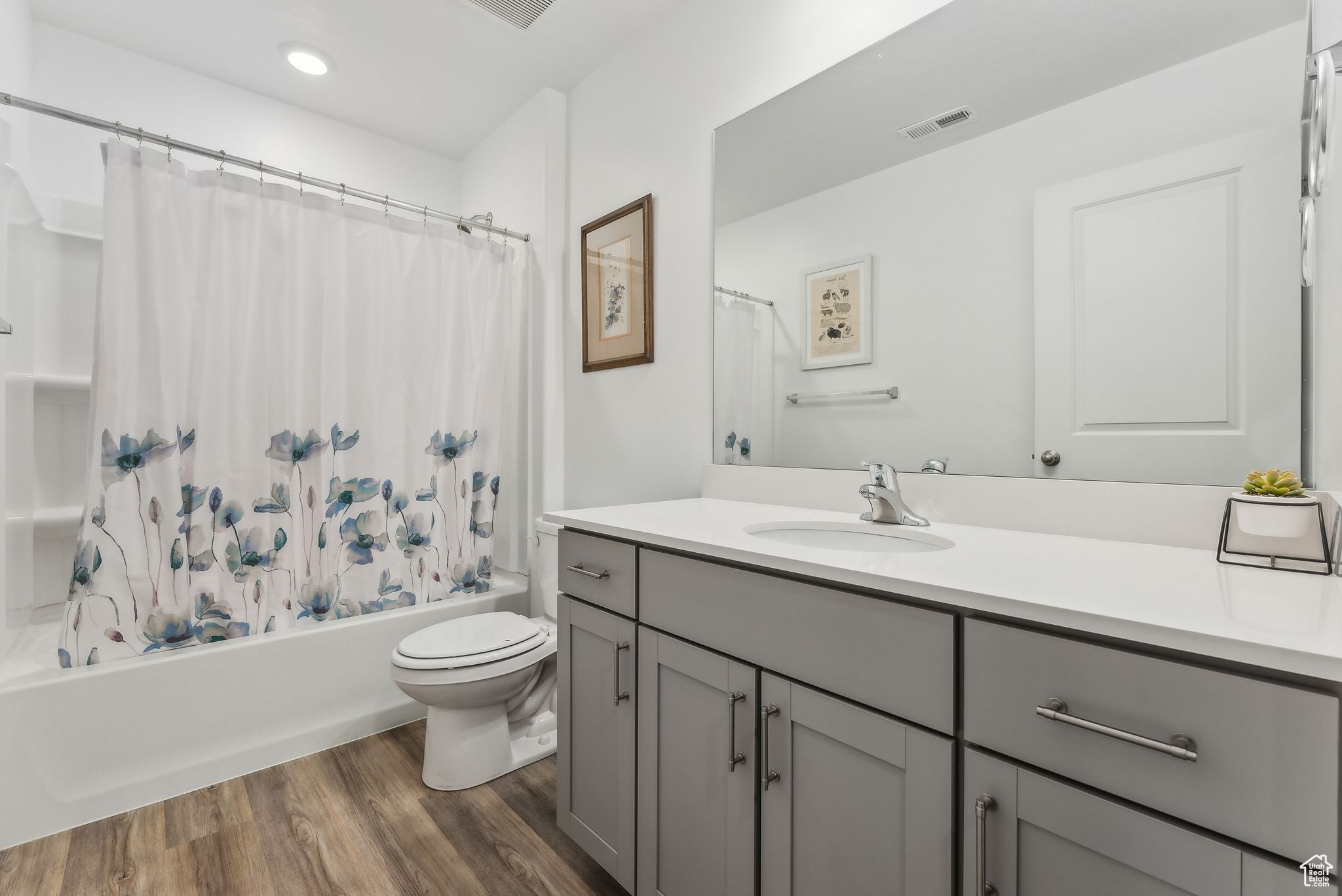 Full bathroom with hardwood / wood-style floors, toilet, vanity, and shower / bathtub combination with curtain