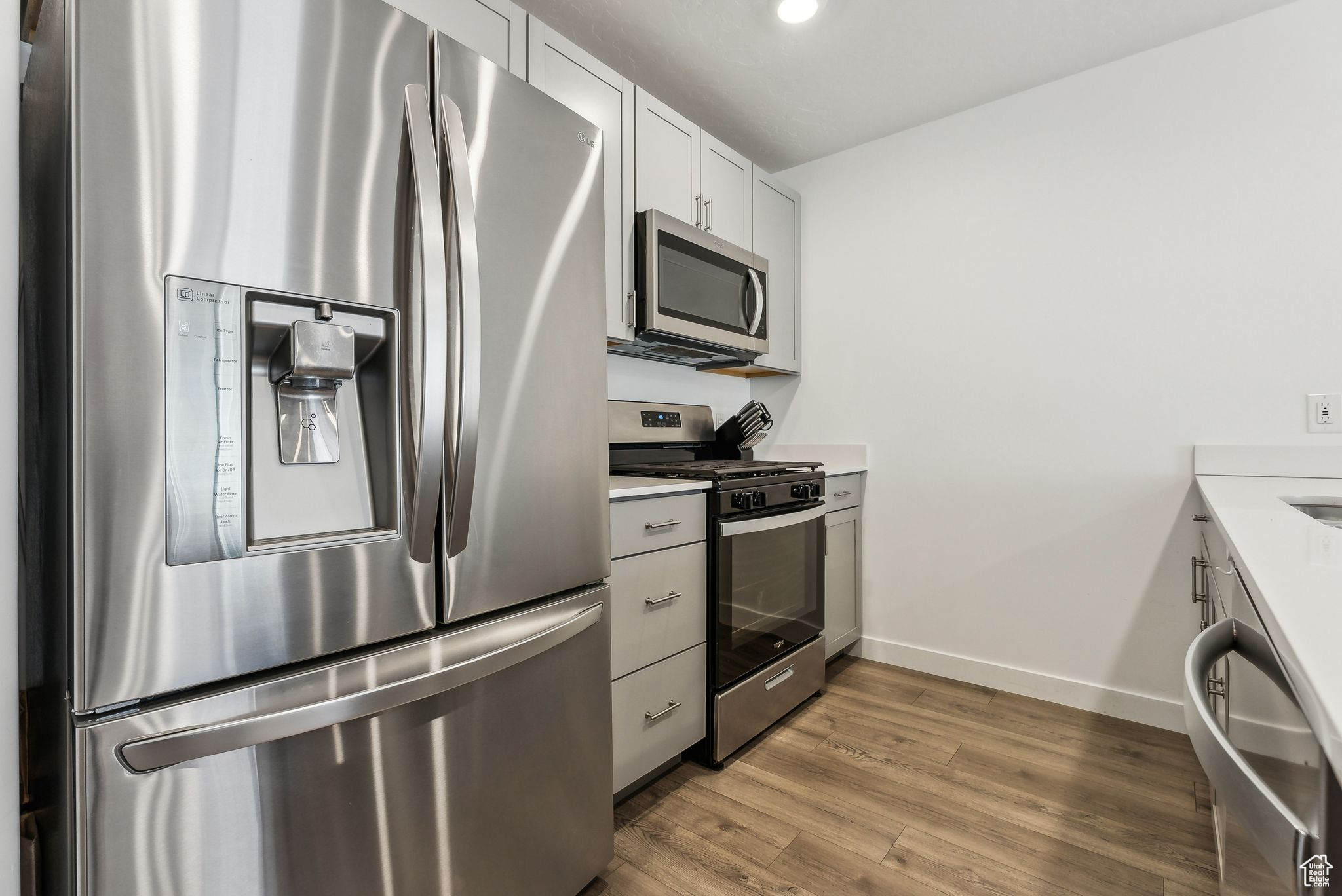 Kitchen featuring white cabinets, hardwood / wood-style floors, and appliances with stainless steel finishes