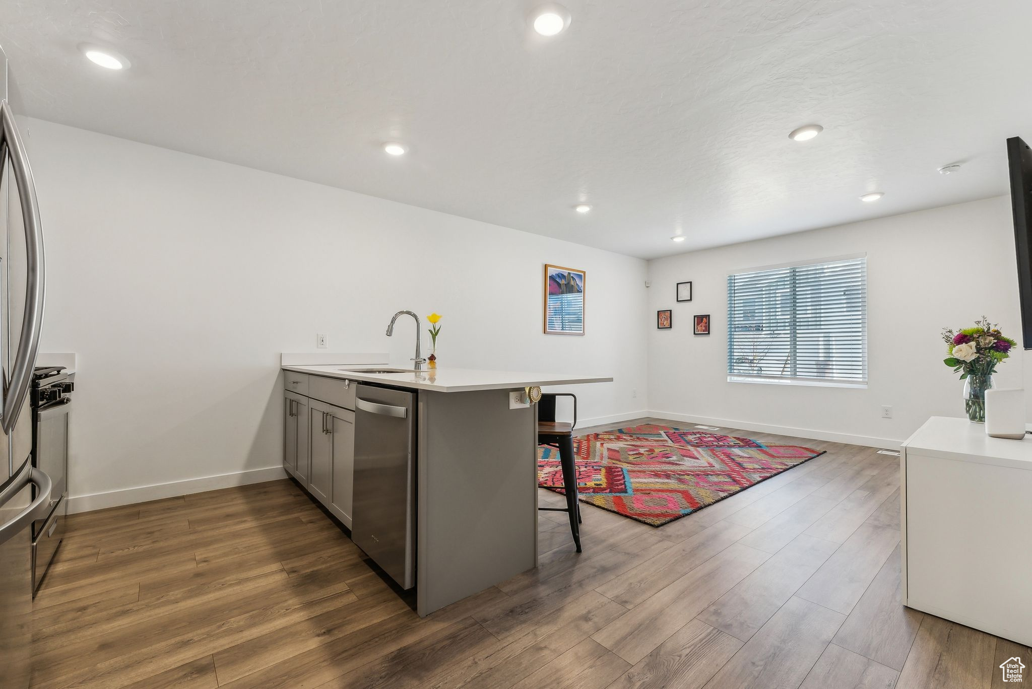 Kitchen with kitchen peninsula, dishwasher, dark hardwood / wood-style flooring, sink, and a kitchen bar