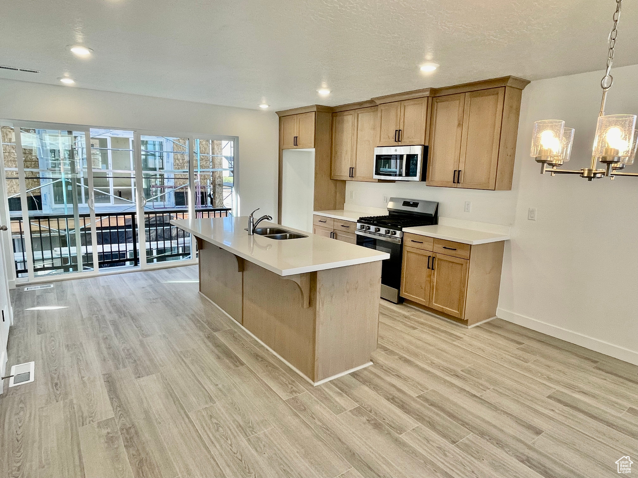 Kitchen with sink, stainless steel appliances, light hardwood / wood-style flooring, and pendant lighting