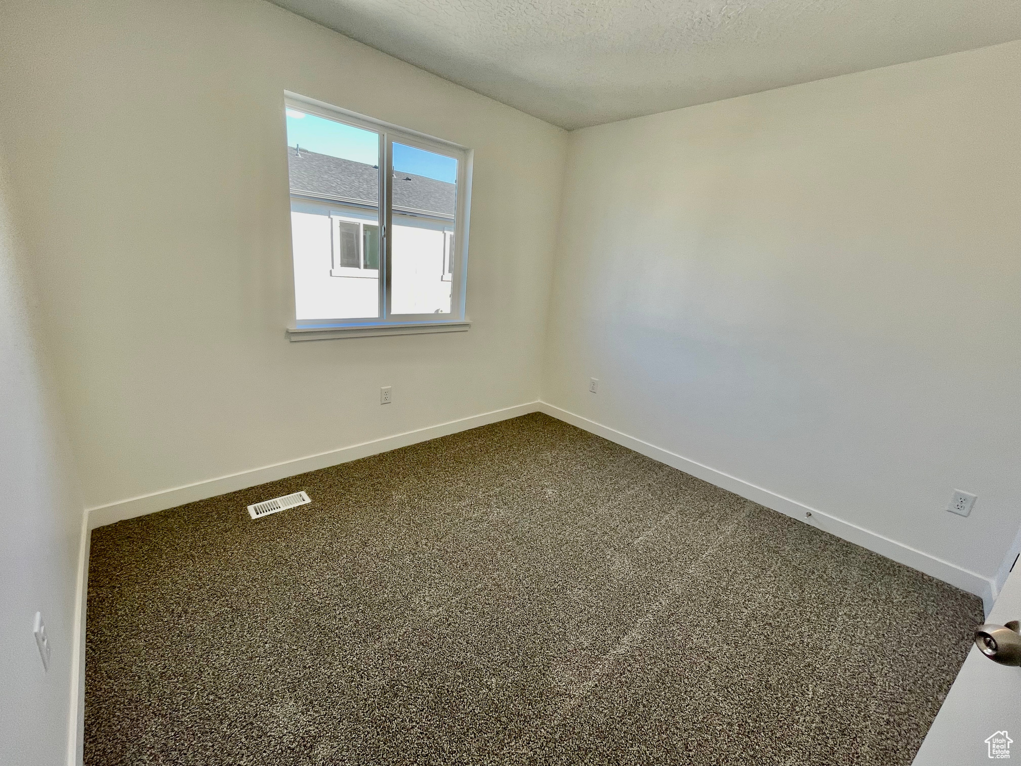 Empty room with carpet flooring and a textured ceiling