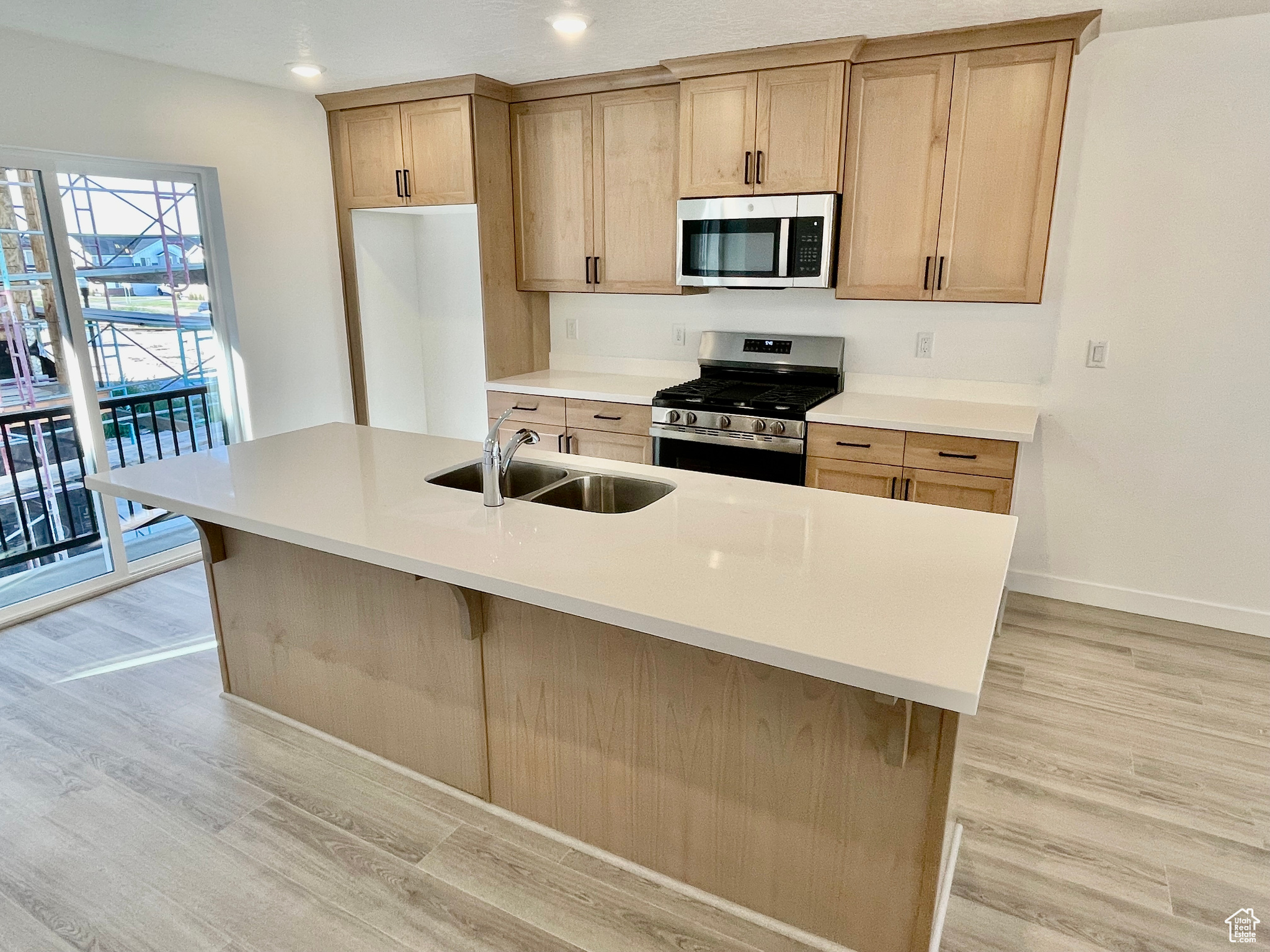 Kitchen featuring sink, an island with sink, light hardwood / wood-style flooring, and stainless steel appliances