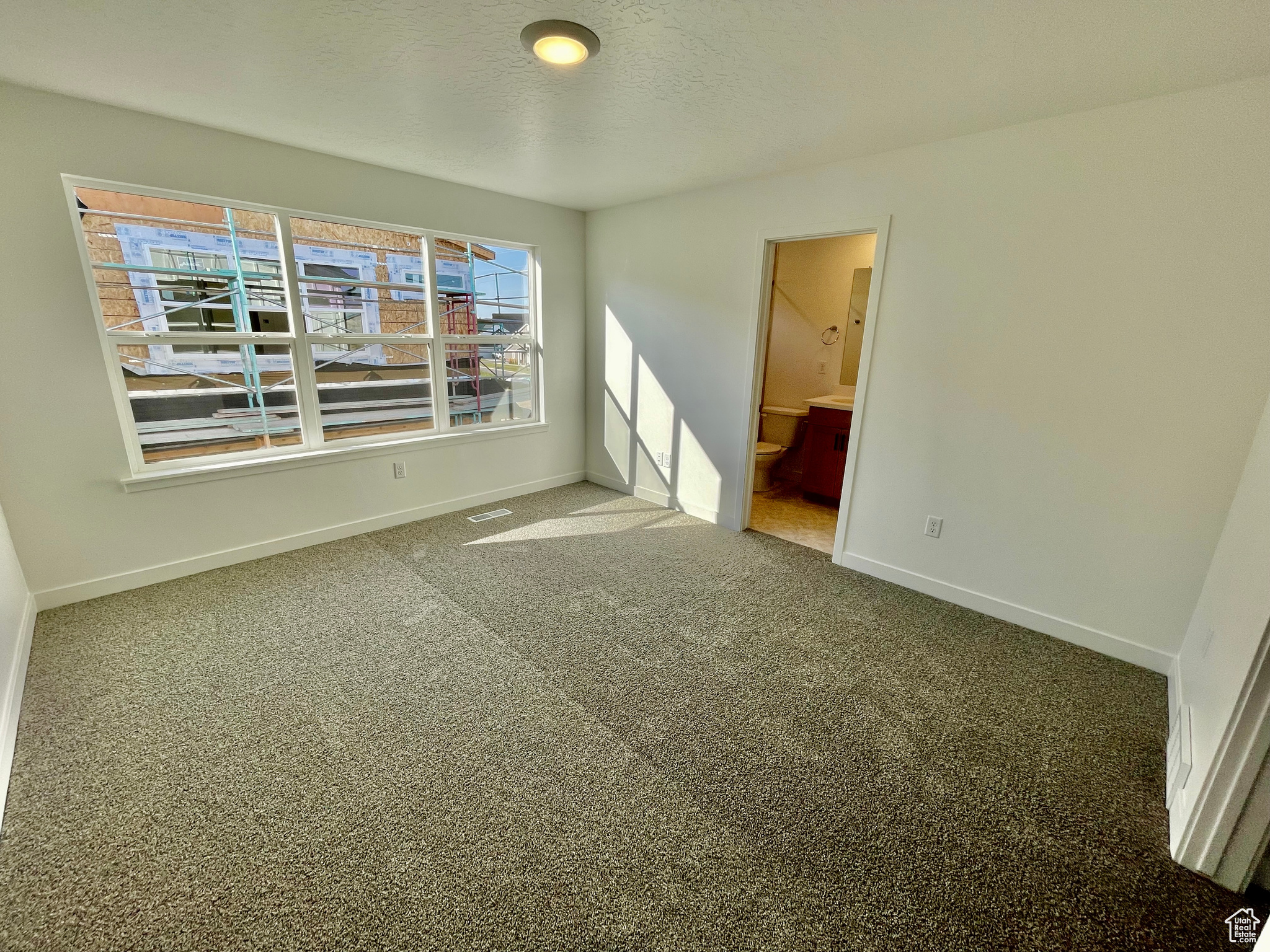 Empty room featuring a textured ceiling and carpet flooring