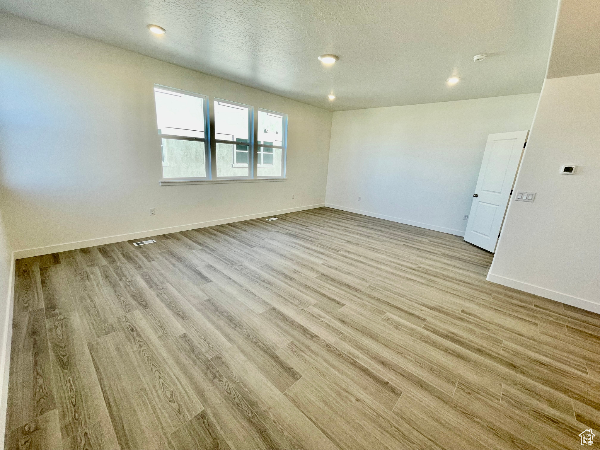 Unfurnished room with light hardwood / wood-style floors and a textured ceiling