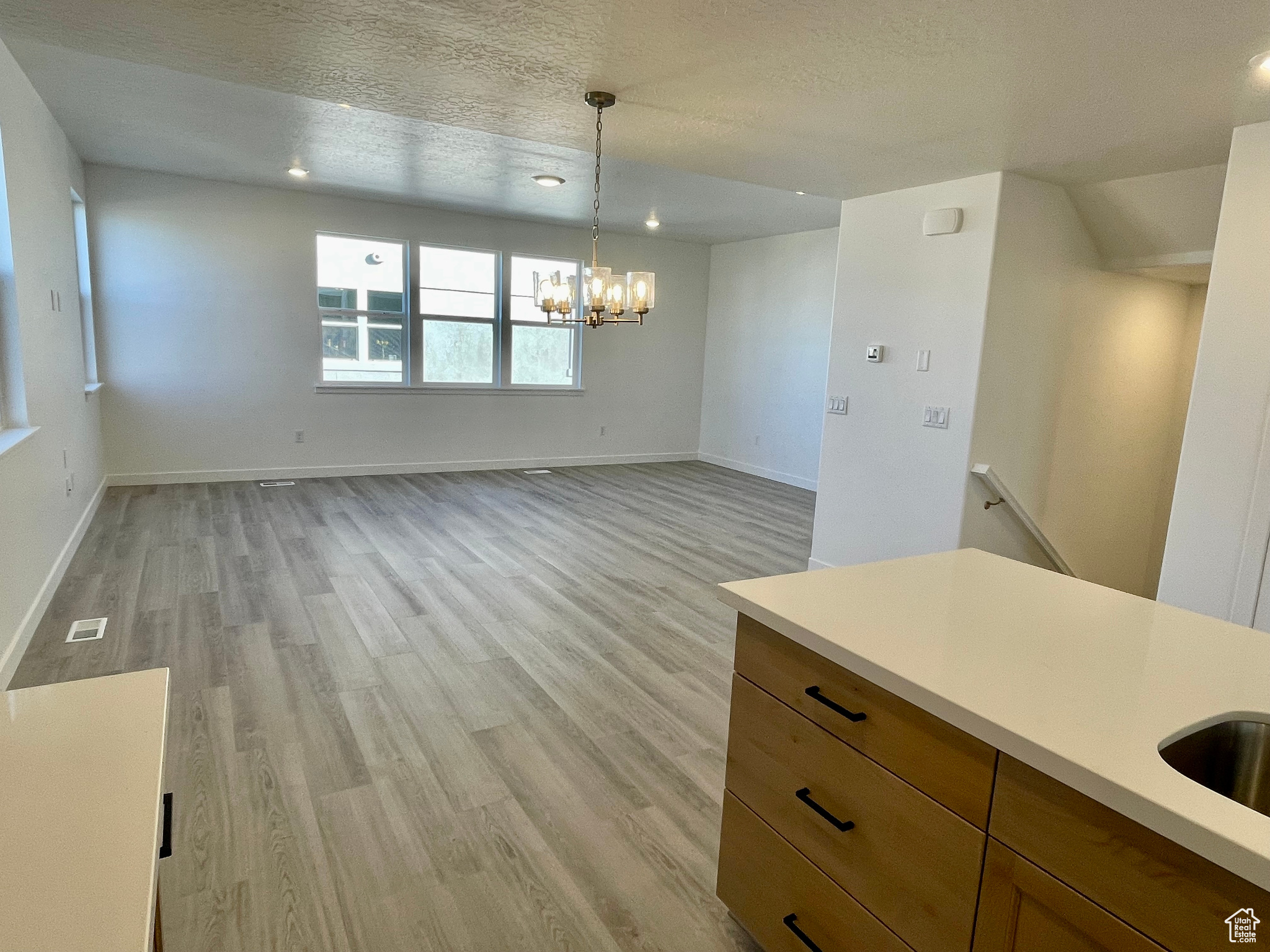 Unfurnished dining area featuring light hardwood / wood-style floors, a textured ceiling, and a notable chandelier