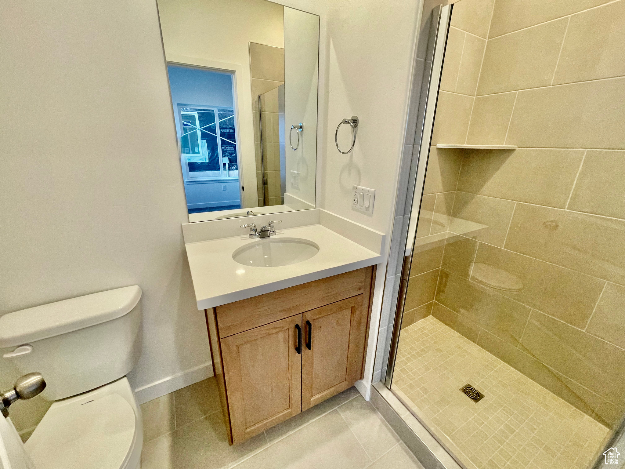 Bathroom with vanity, toilet, tile patterned floors, and a shower with shower door