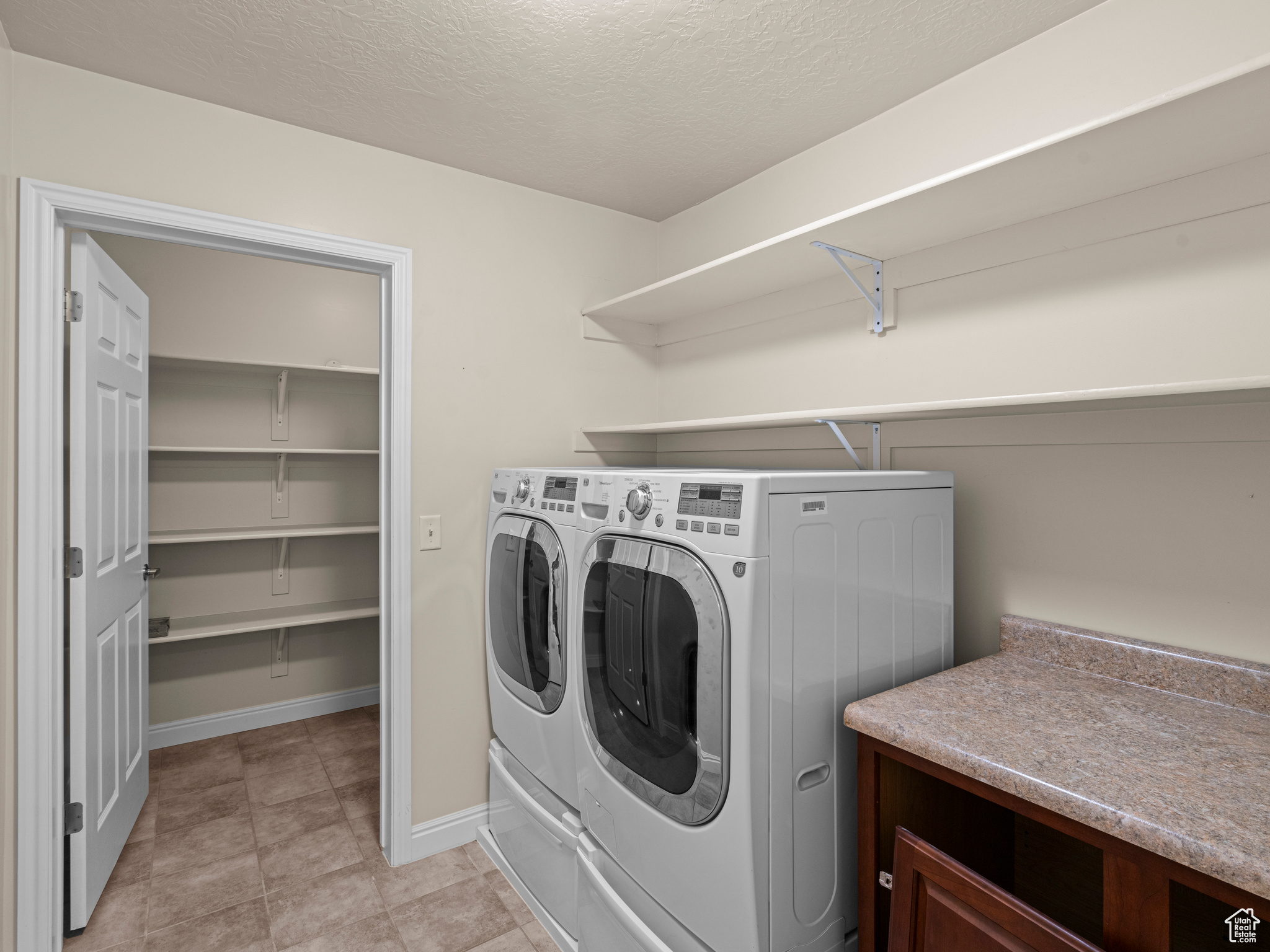 Laundry area featuring a textured ceiling and washing machine and clothes dryer