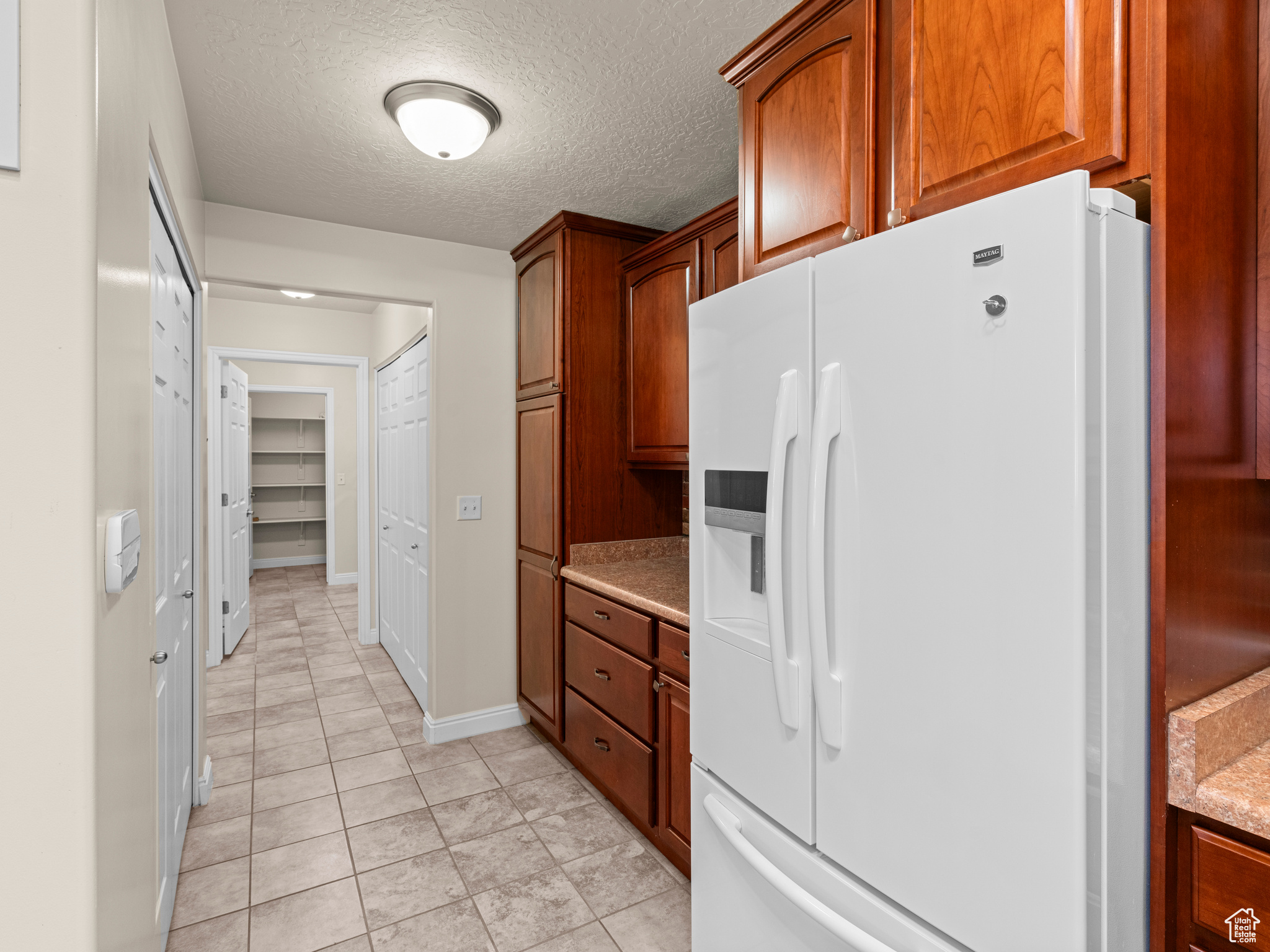 Kitchen featuring white refrigerator with ice dispenser and a textured ceiling