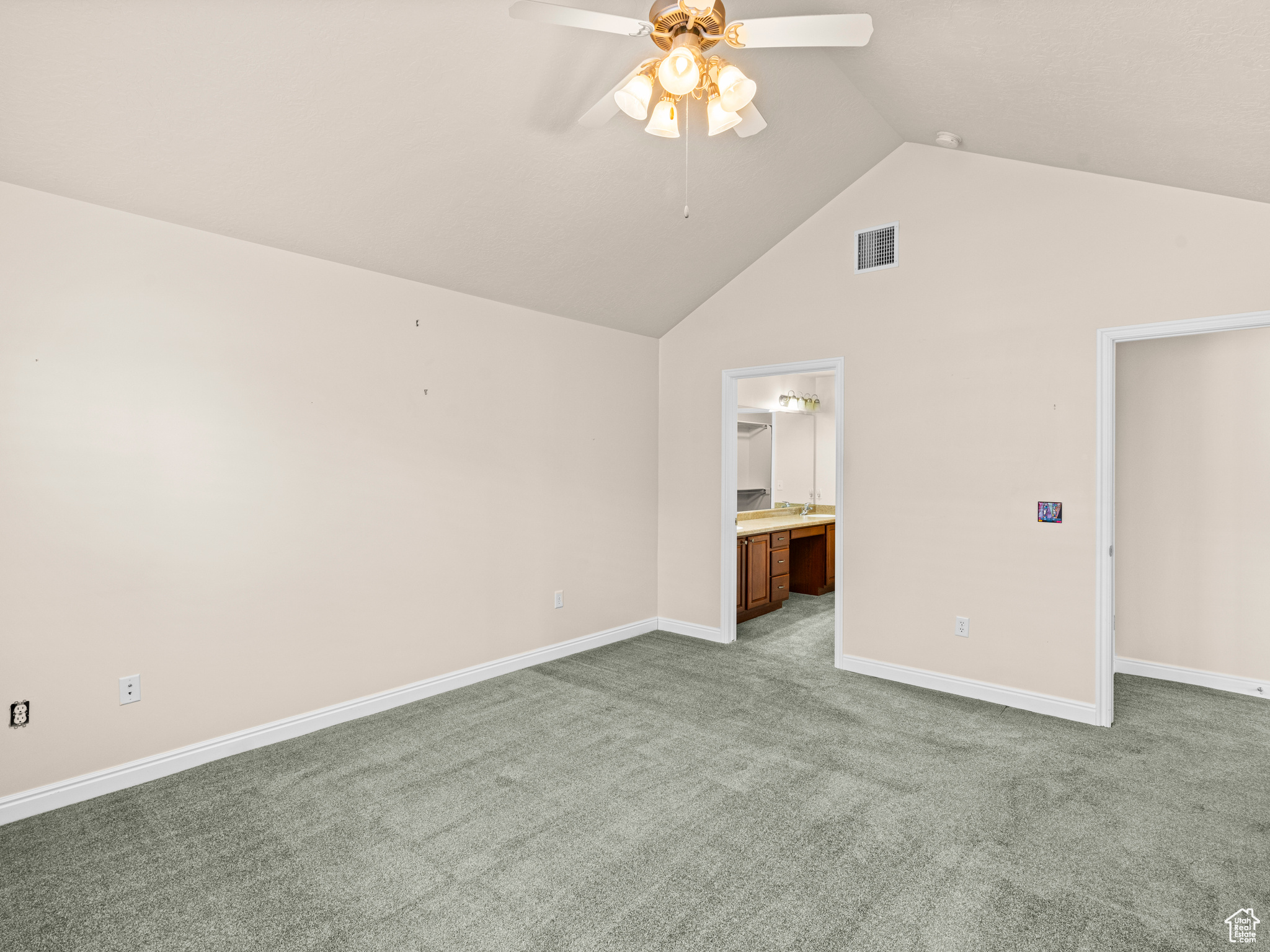 Interior space with ceiling fan, connected bathroom, lofted ceiling, and carpet flooring