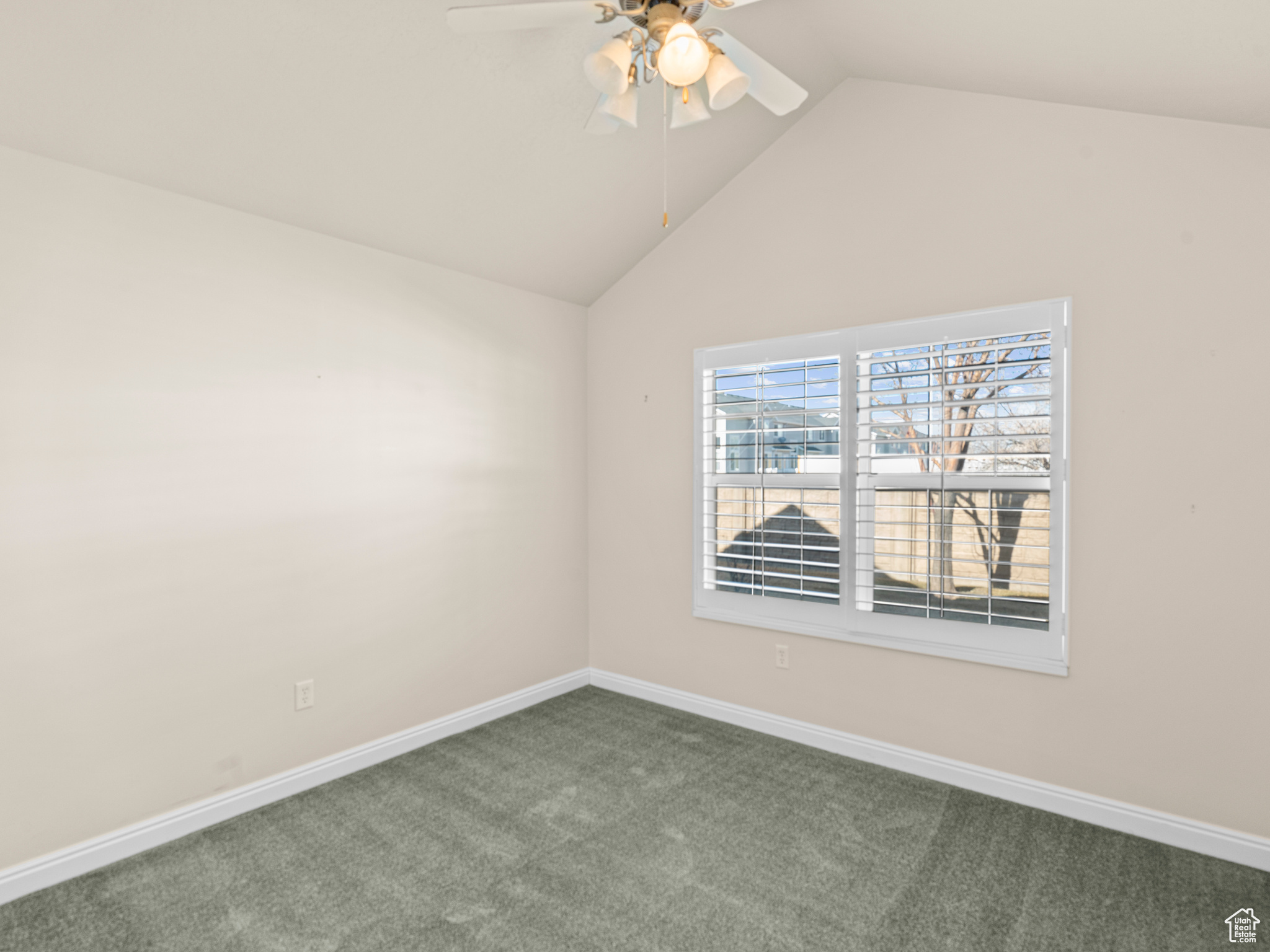 Carpeted empty room with vaulted ceiling and ceiling fan