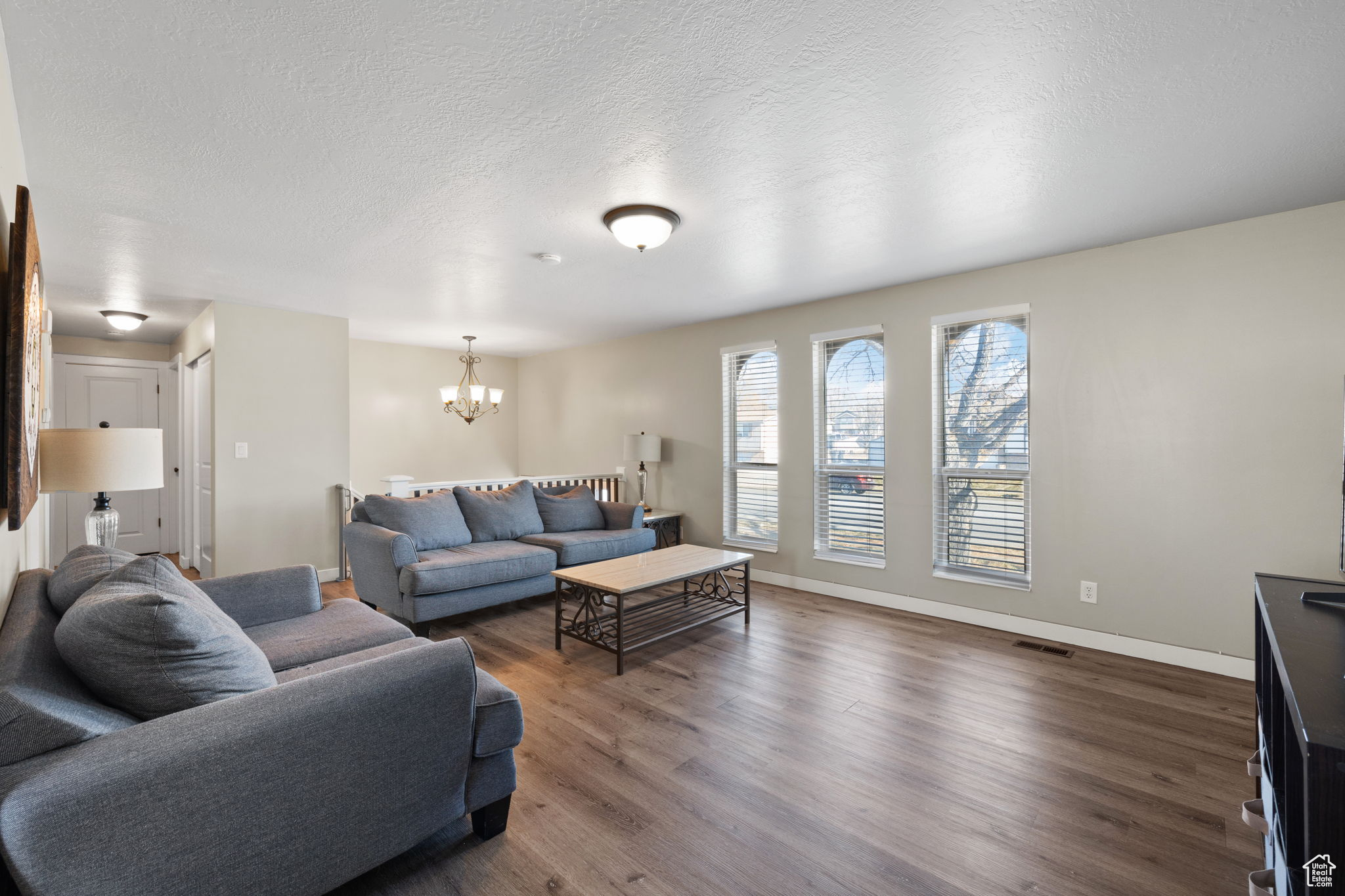 Living room with a chandelier, a textured ceiling, and dark hardwood / wood-style flooring