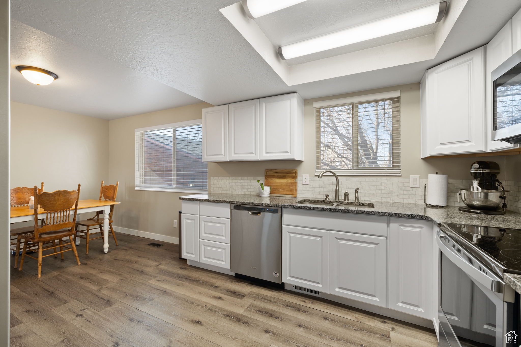 Kitchen featuring sink, white cabinets, dark stone countertops, and stainless steel appliances