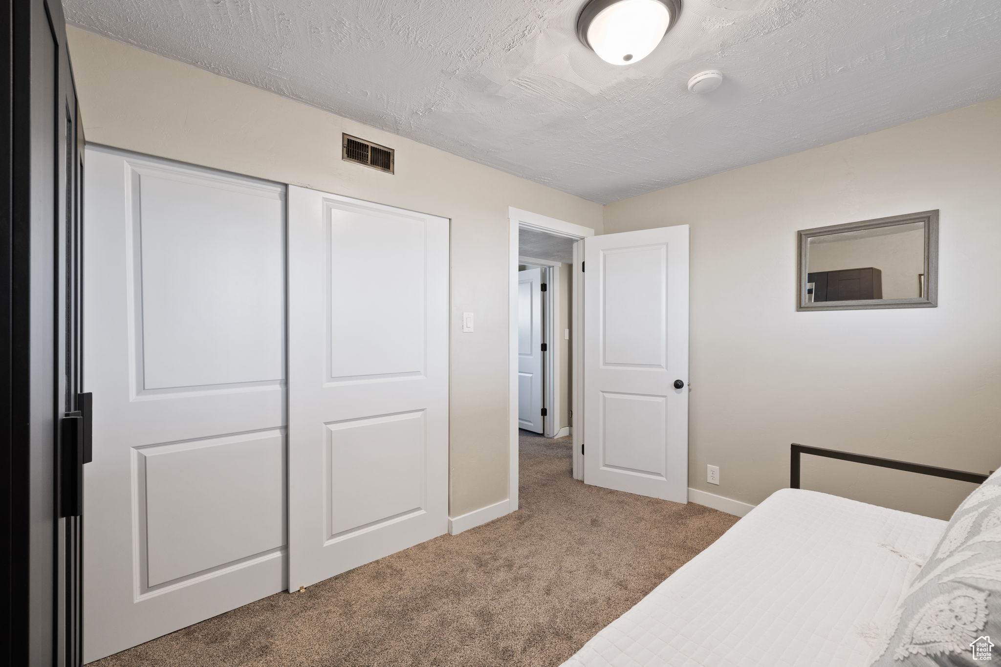 Carpeted bedroom featuring a closet and a textured ceiling