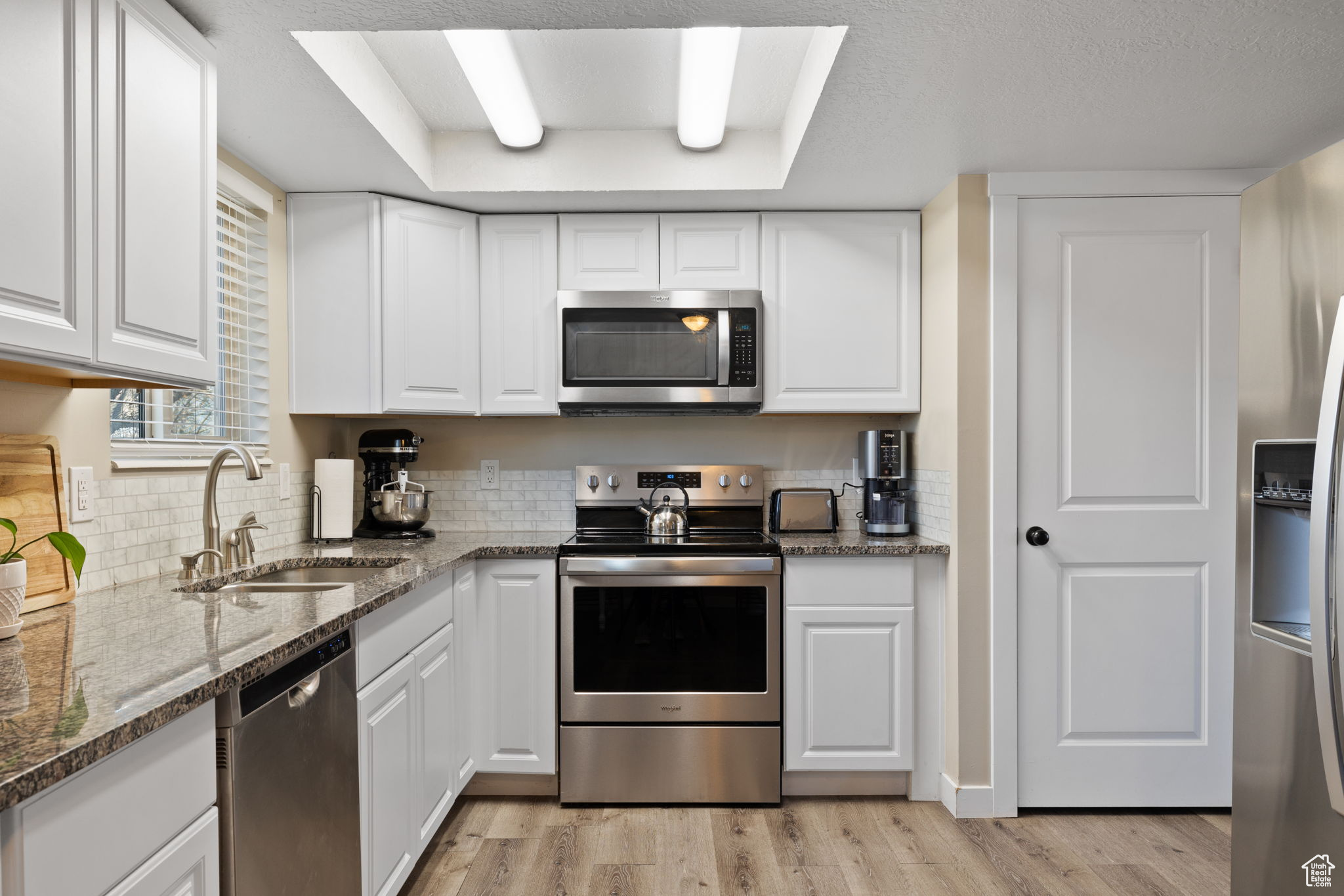 Kitchen featuring white cabinets, stainless steel appliances, and sink