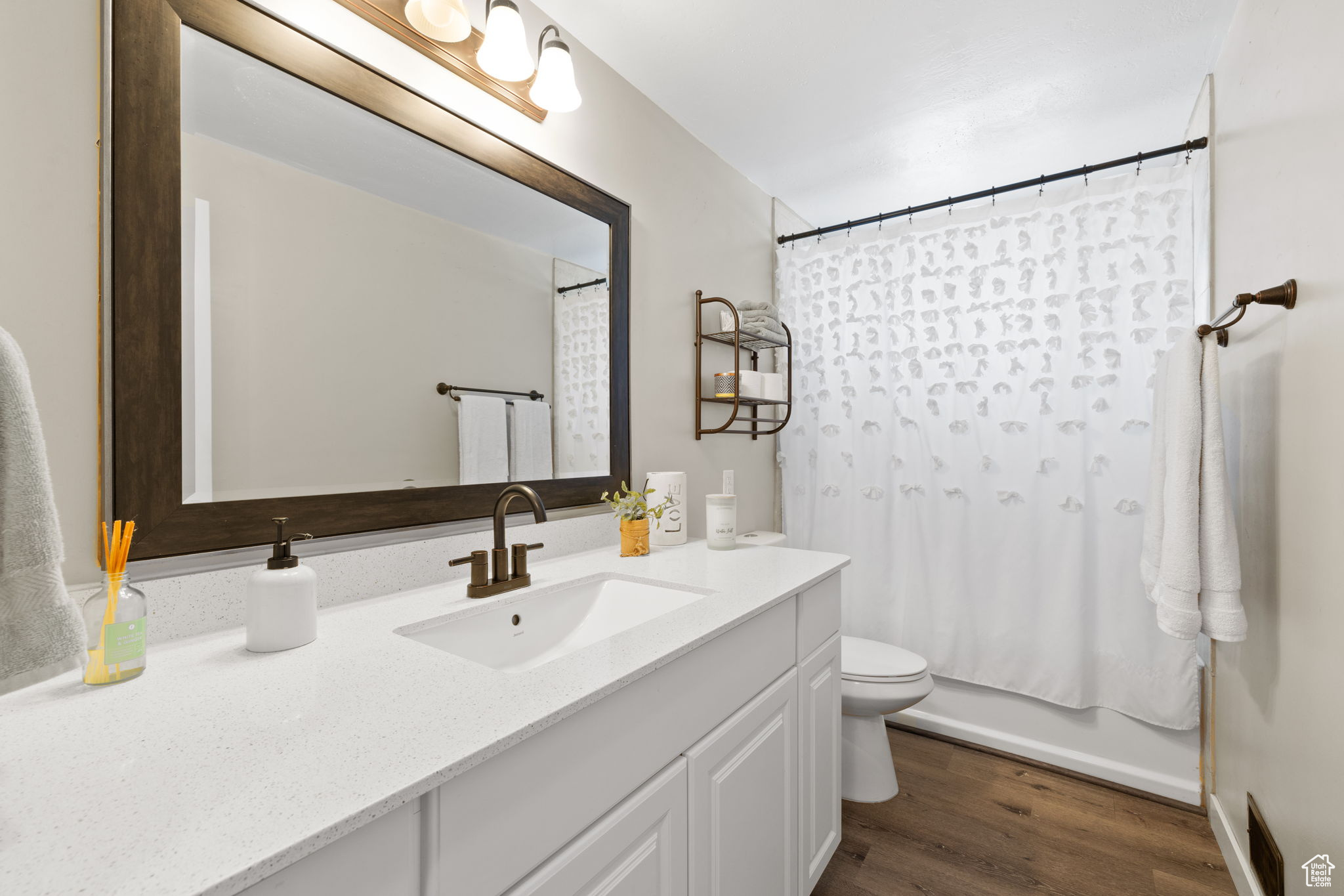 Full bathroom featuring wood-type flooring, toilet, shower / tub combo with curtain, and vanity