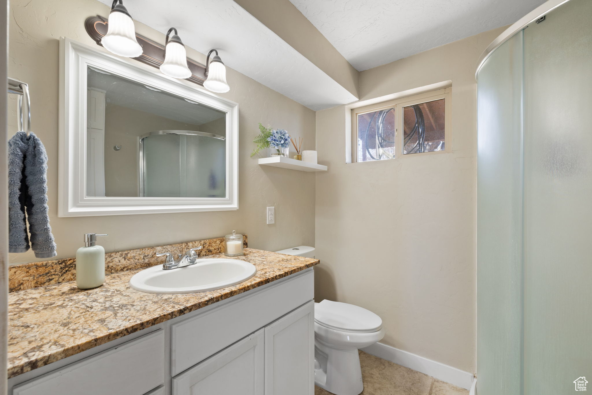 Bathroom featuring toilet, tile patterned flooring, walk in shower, and vanity