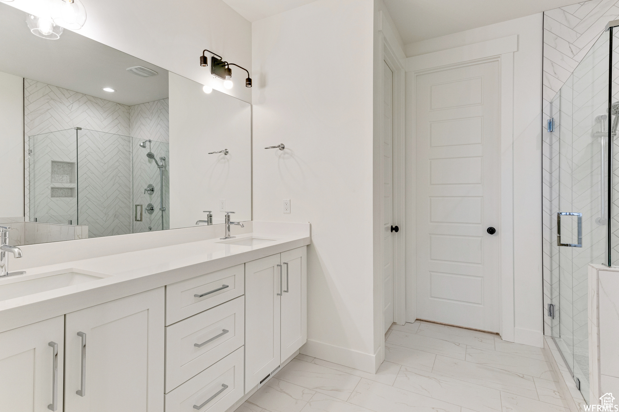 Bathroom featuring a shower with door and vanity