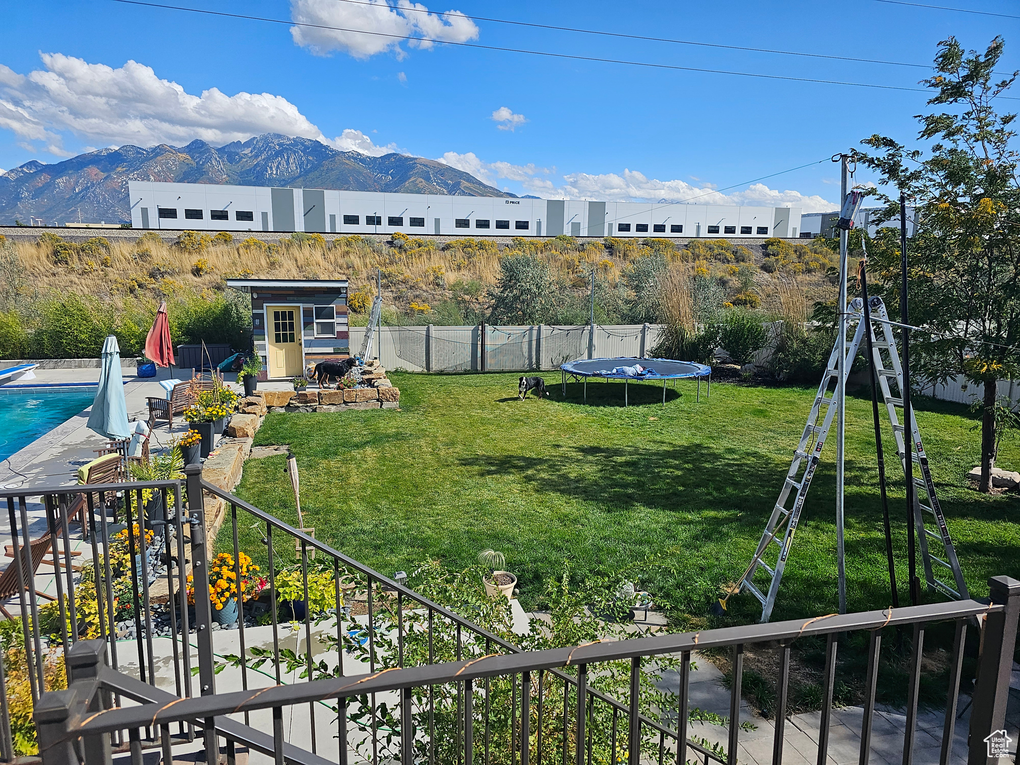 View of yard with a fenced in pool, an outdoor structure, a mountain view, and a trampoline