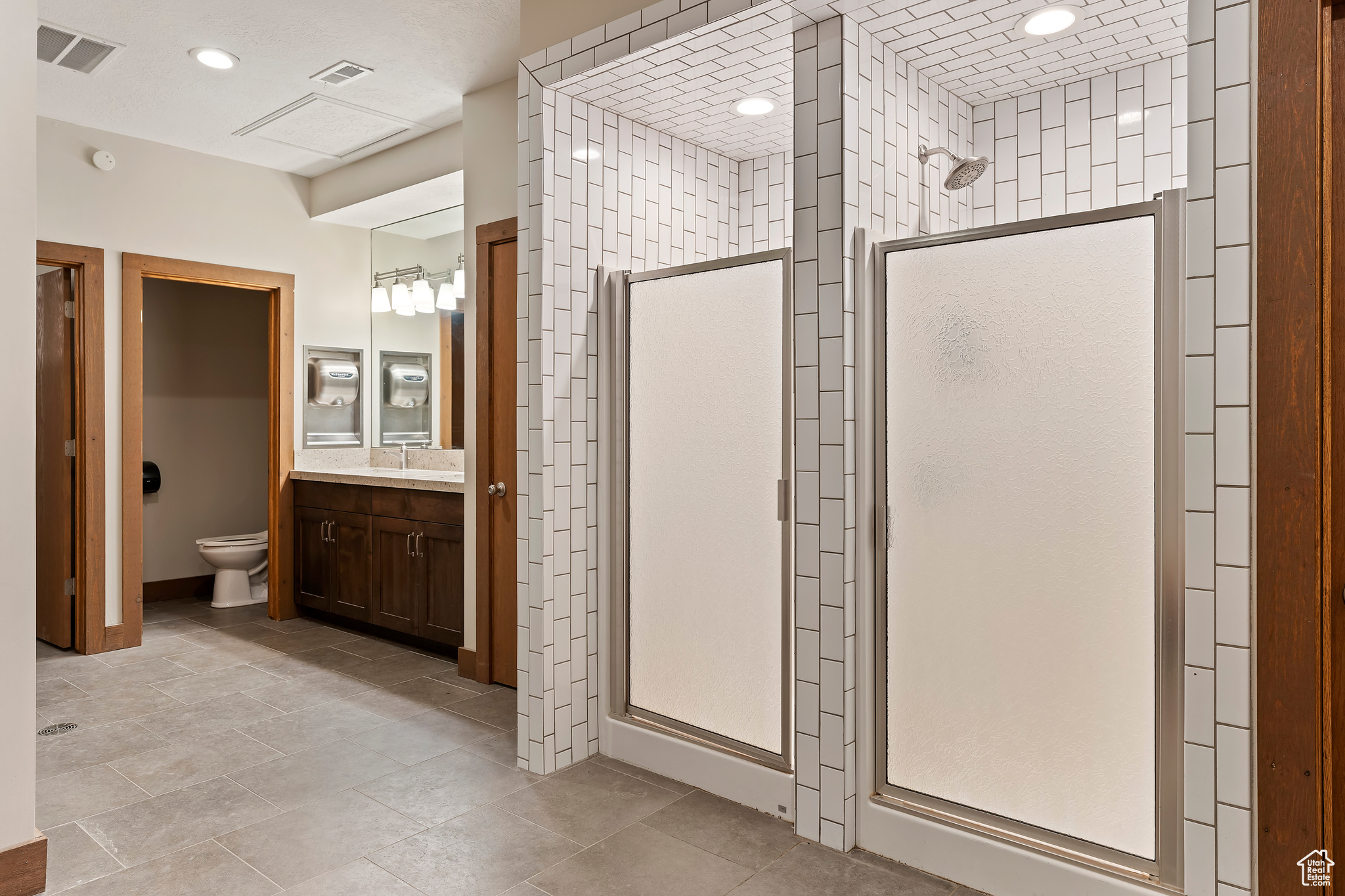 Bathroom featuring walk in shower, vanity, and toilet