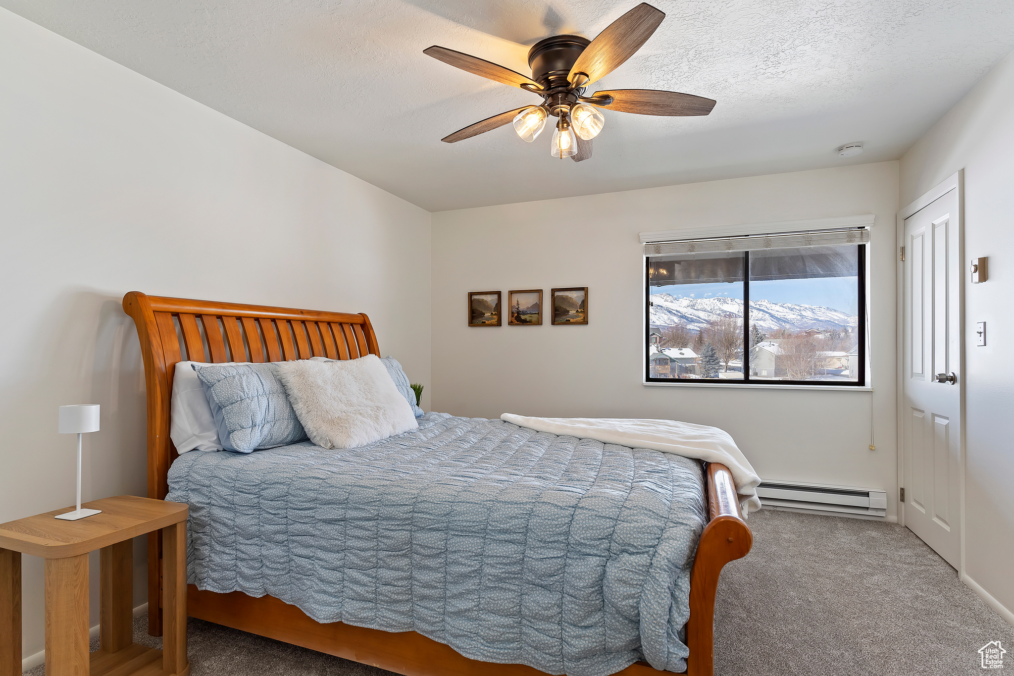 Carpeted bedroom with a textured ceiling, a baseboard radiator, and ceiling fan