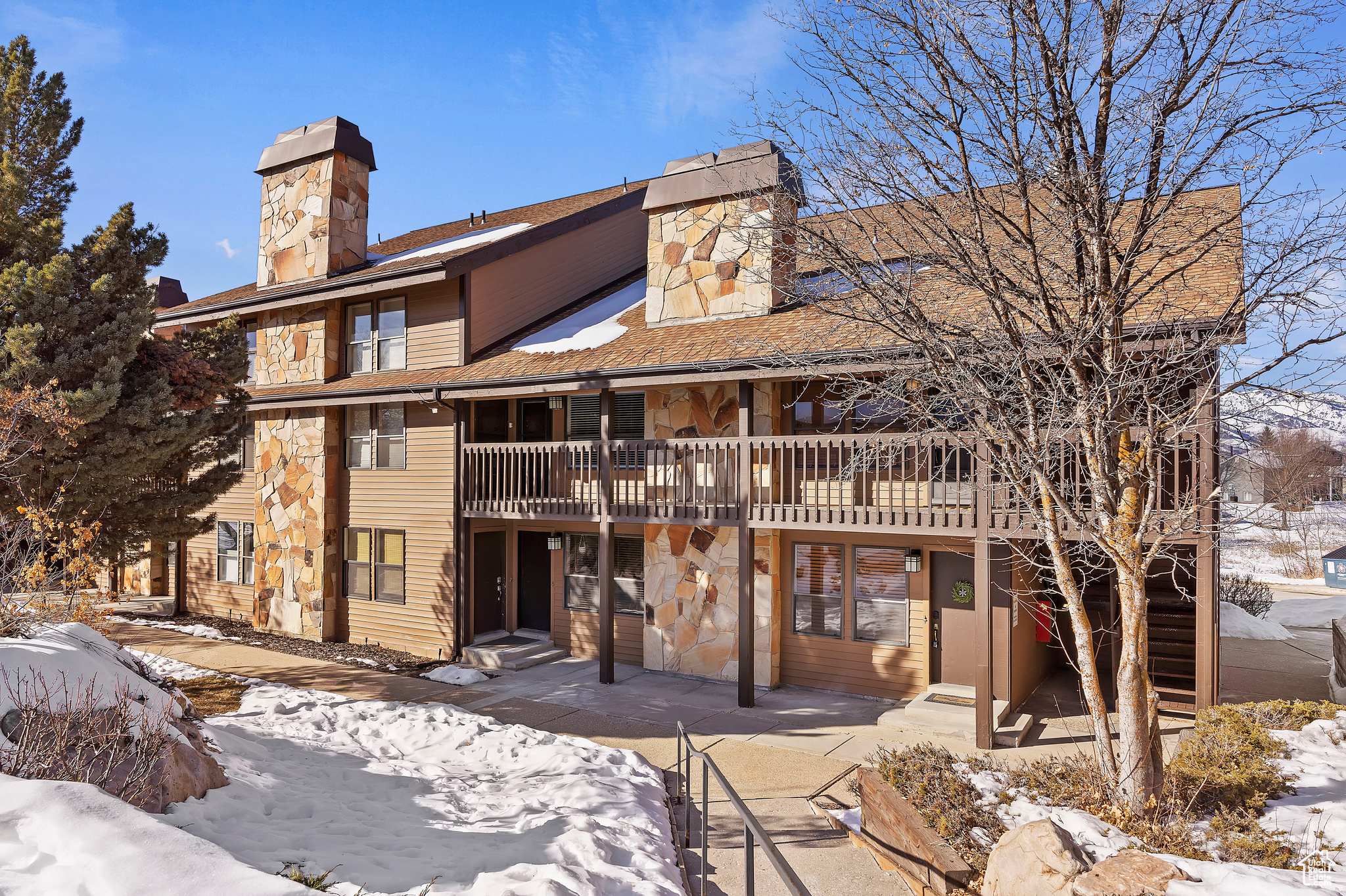 Snow covered rear of property featuring a wooden deck