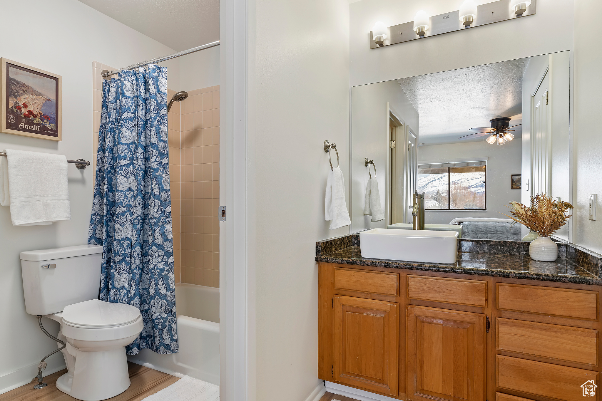 Full bathroom featuring toilet, a textured ceiling, vanity, shower / bath combo, and ceiling fan