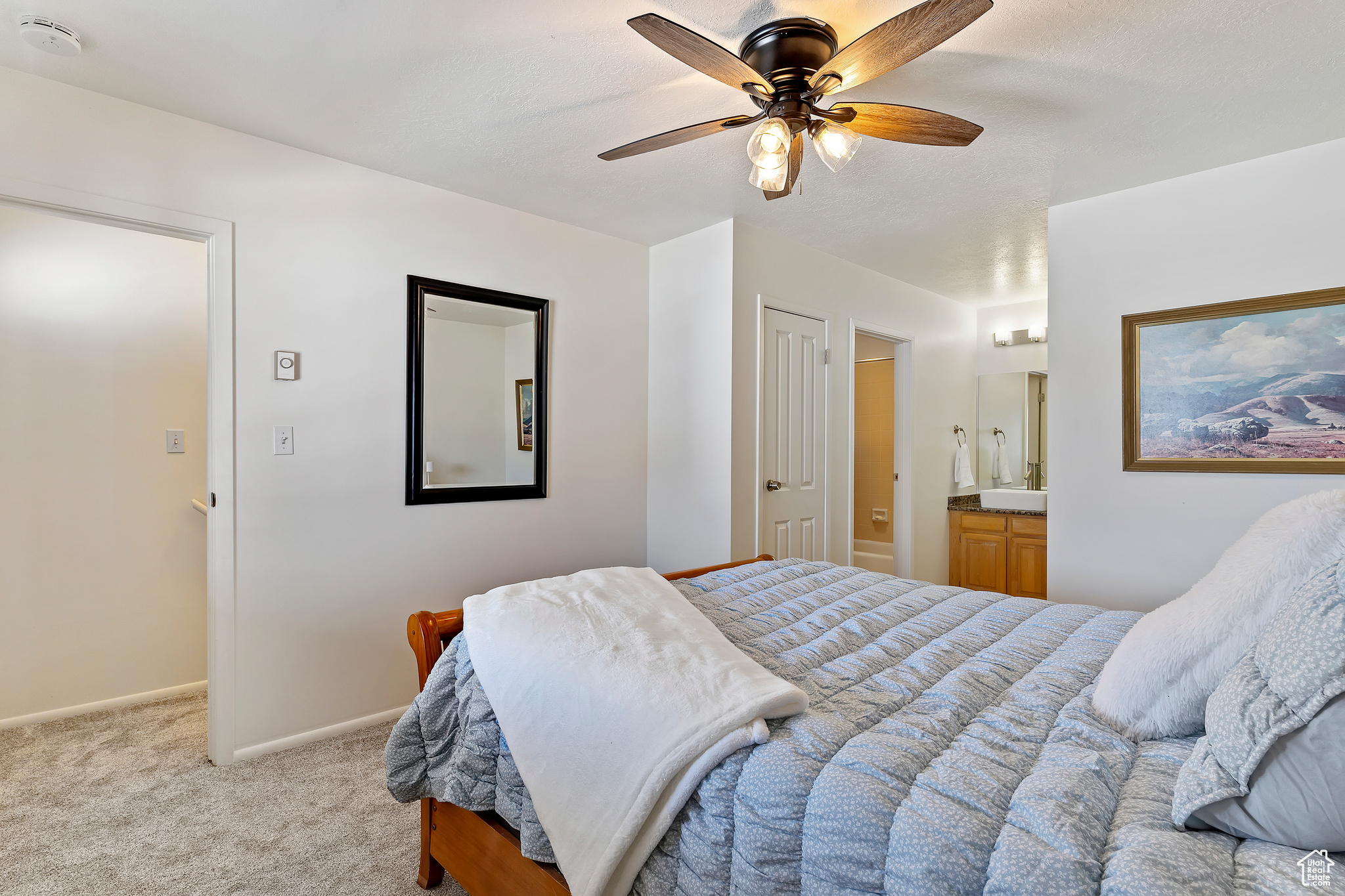 Bedroom featuring a closet, light colored carpet, ceiling fan, and ensuite bath