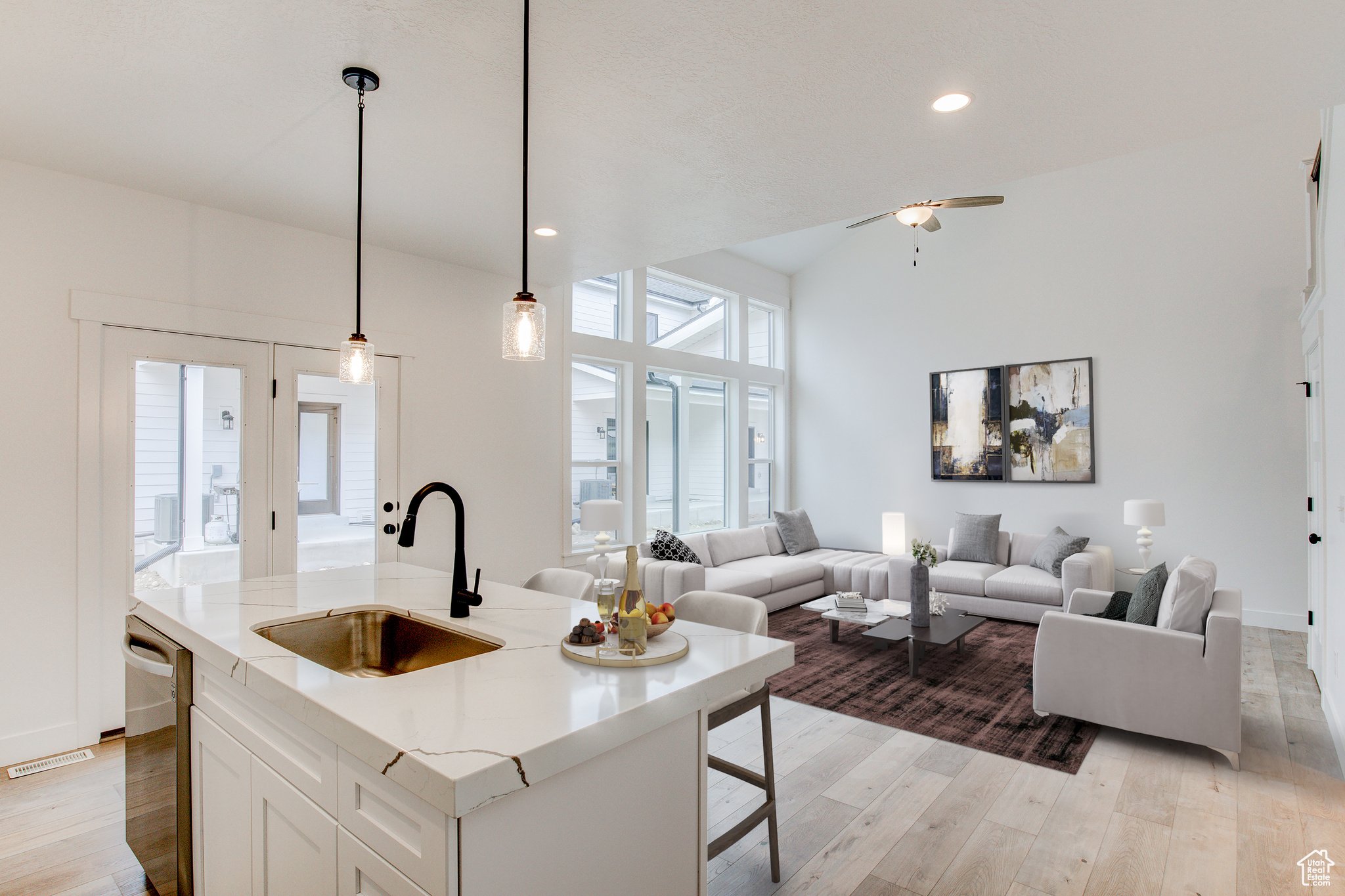 Kitchen featuring sink, white cabinetry, decorative light fixtures, a center island with sink, and dishwasher