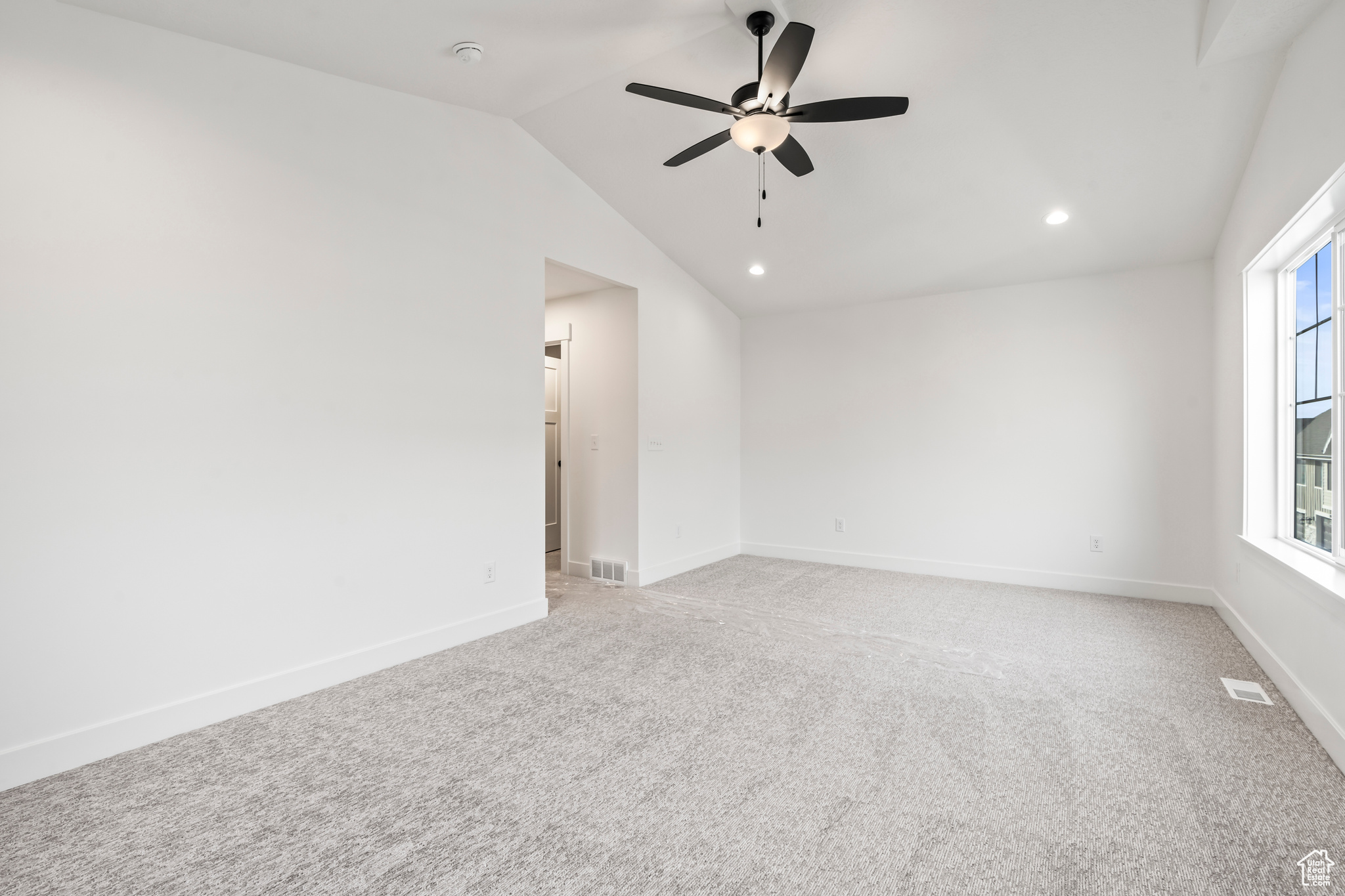 Carpeted spare room with lofted ceiling and ceiling fan