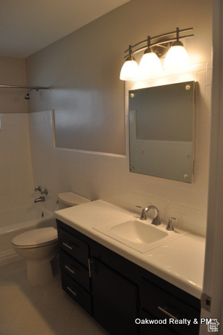 Full bathroom with washtub / shower combination, tile patterned floors, tile walls, vanity, and backsplash