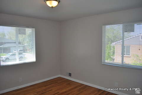 Empty room featuring plenty of natural light and dark wood-type flooring