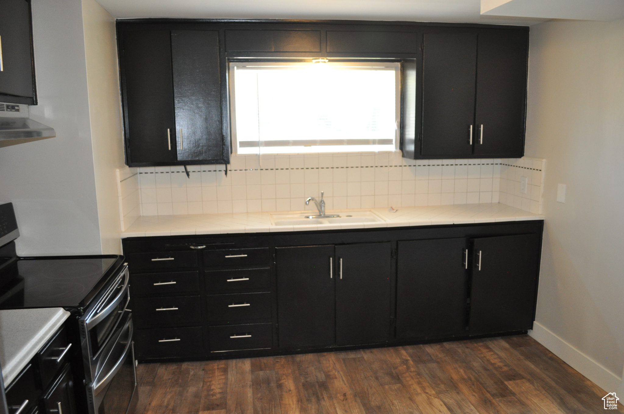 Kitchen with range with two ovens, extractor fan, sink, and dark hardwood / wood-style floors