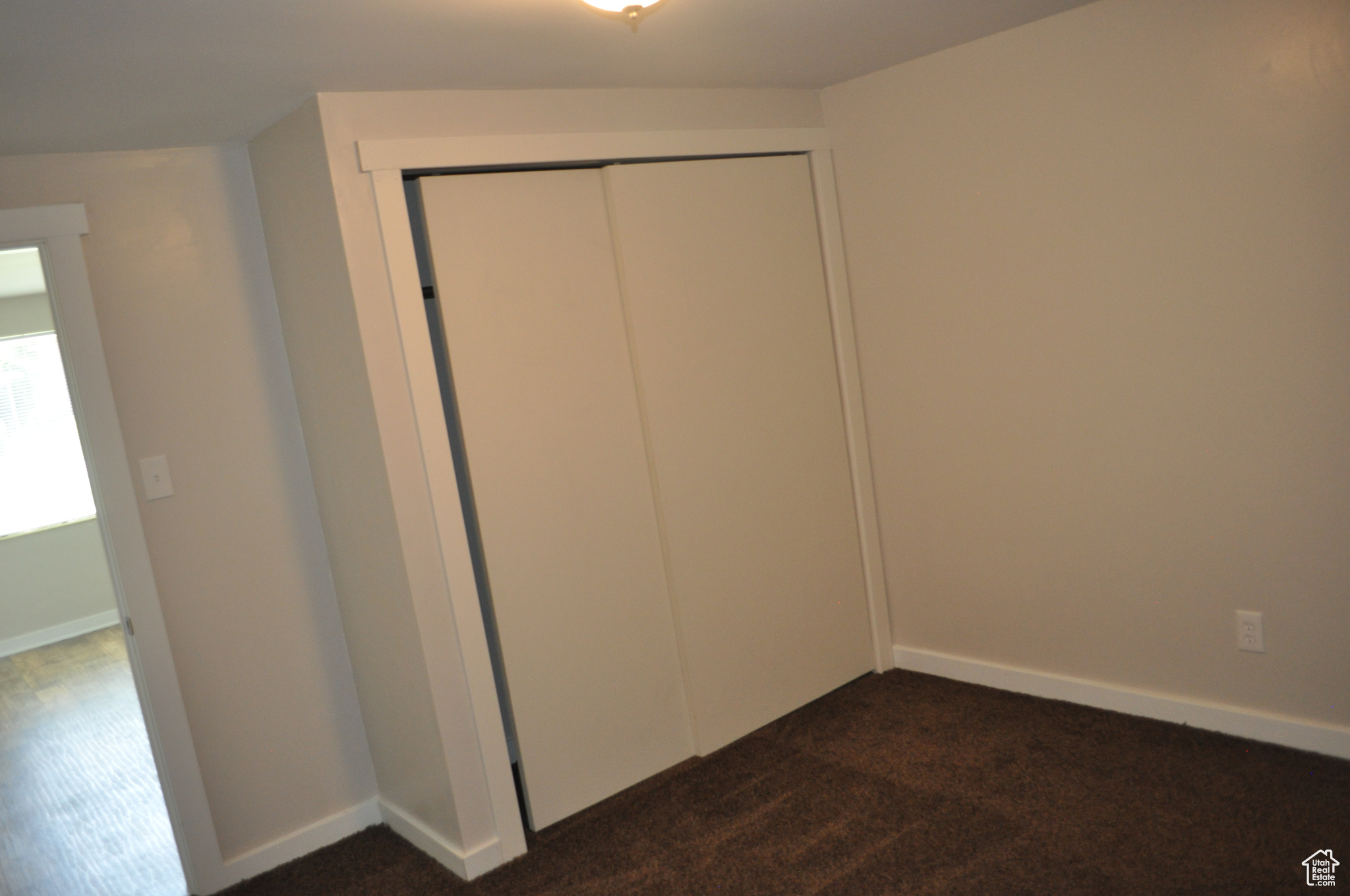 Unfurnished bedroom featuring dark colored carpet and a closet