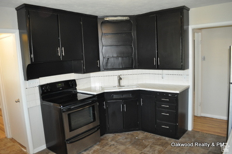 Kitchen featuring sink, stainless steel electric range, and decorative backsplash