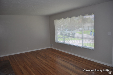 Empty room with a healthy amount of sunlight and dark wood-type flooring