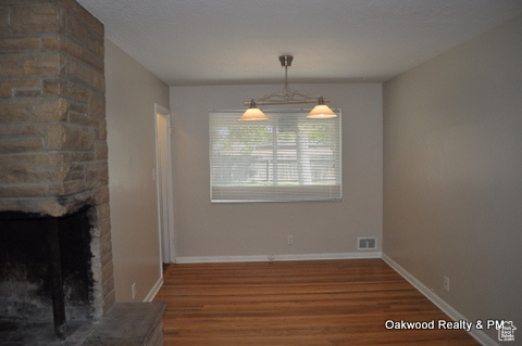 Unfurnished dining area with dark wood-type flooring and a fireplace