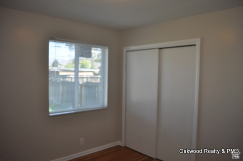 Unfurnished bedroom featuring dark hardwood / wood-style flooring and a closet