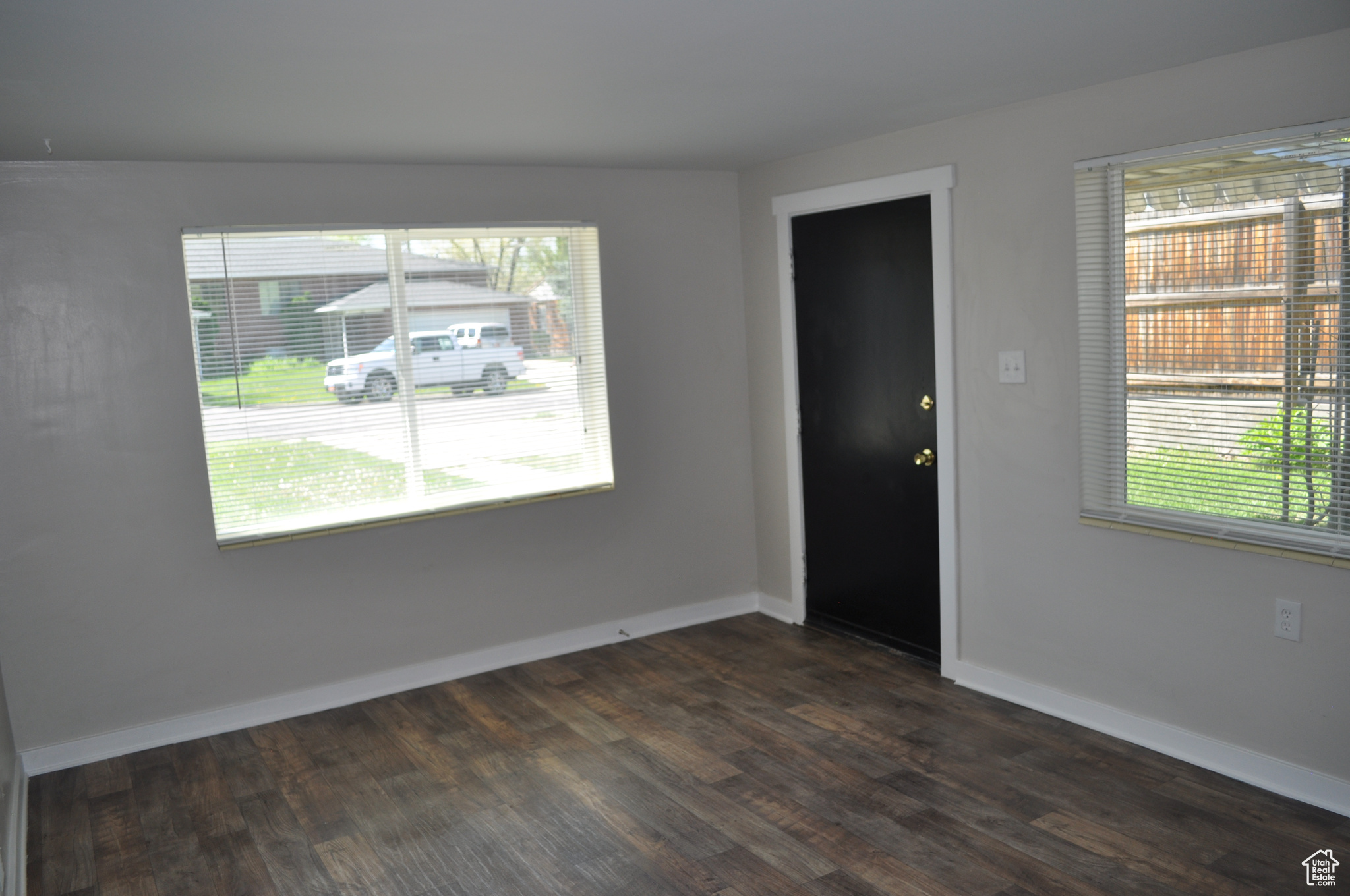 Spare room featuring dark wood-type flooring and a wealth of natural light