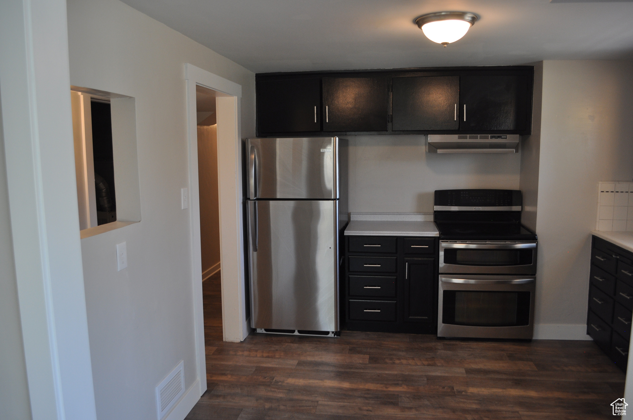 Kitchen featuring backsplash, dark wood-type flooring, and appliances with stainless steel finishes