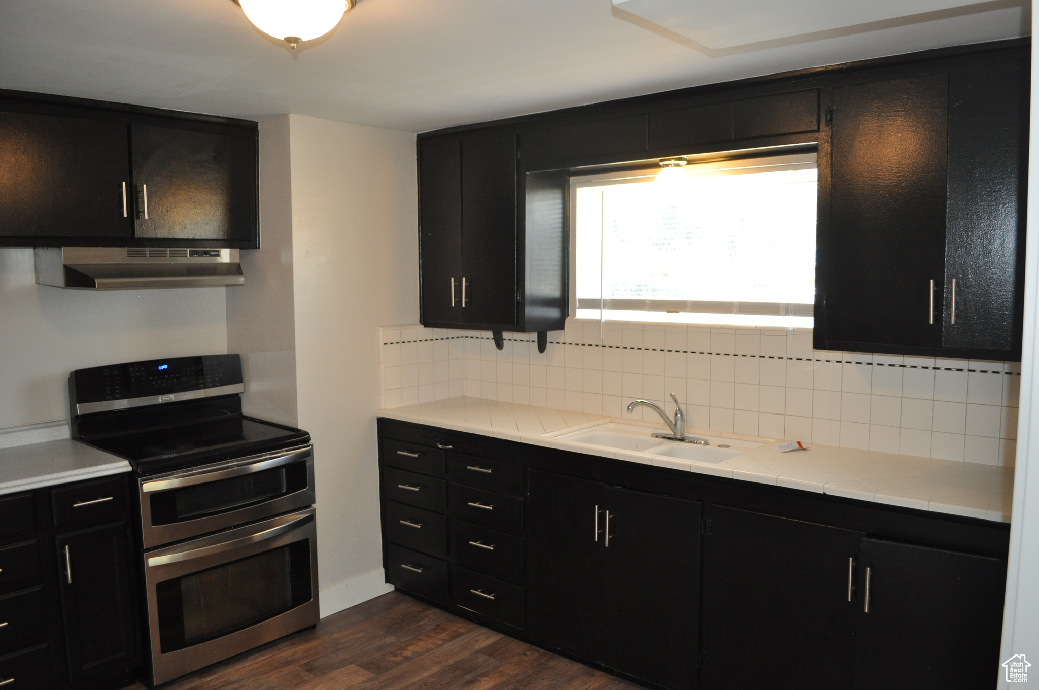 Kitchen featuring double oven range, dark hardwood / wood-style flooring, sink, and backsplash