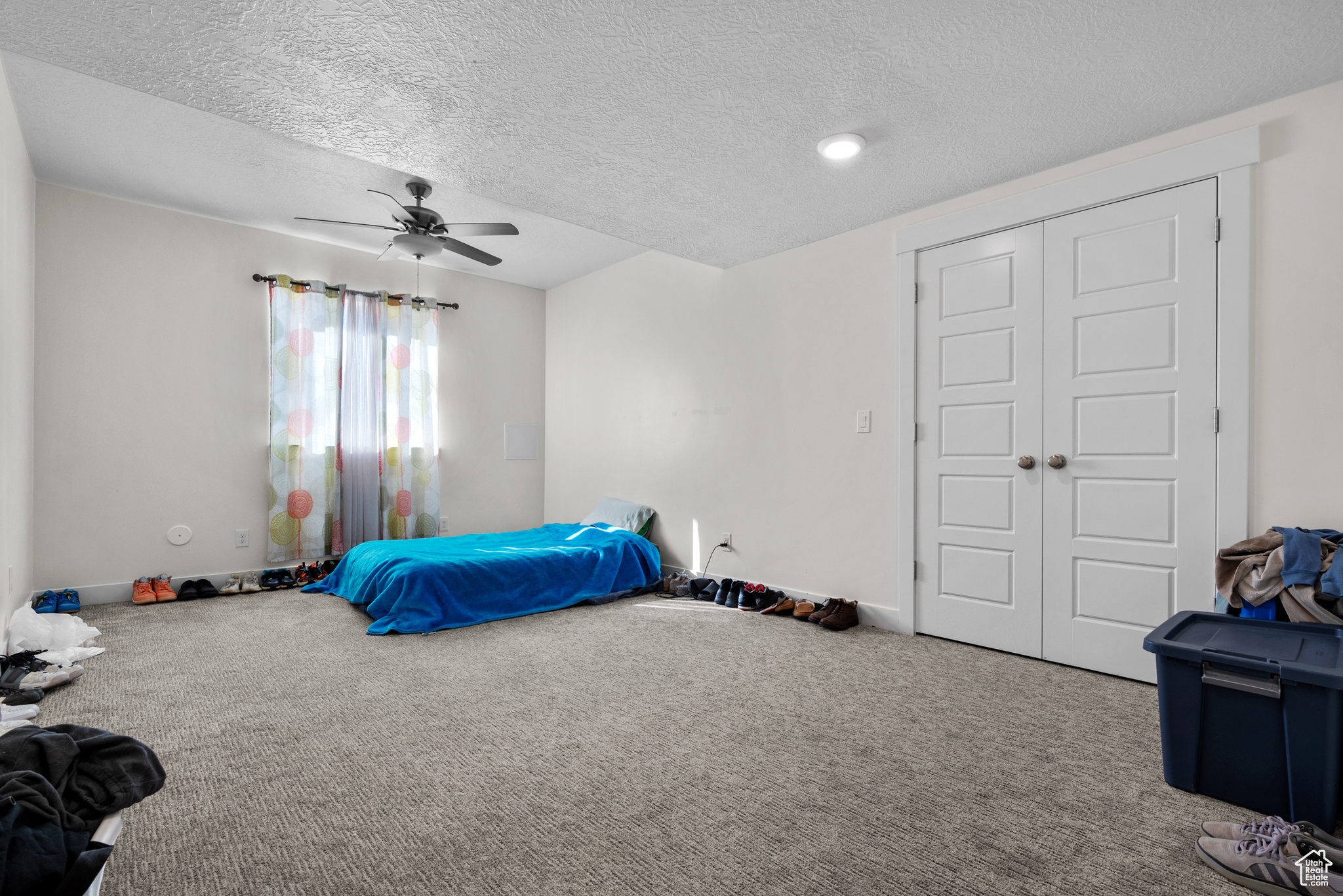 Bedroom featuring carpet, a textured ceiling, ceiling fan, and a closet